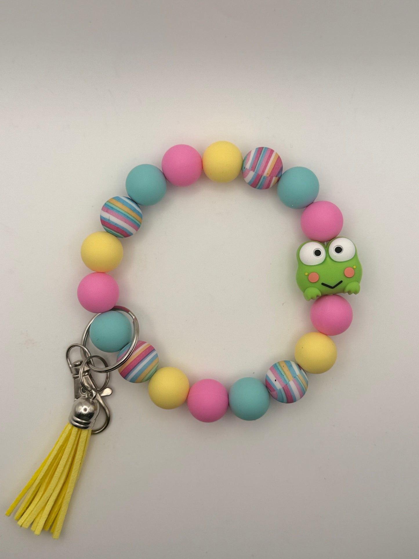 Colorful beaded keychain with a frog charm and yellow tassel on a light gray background