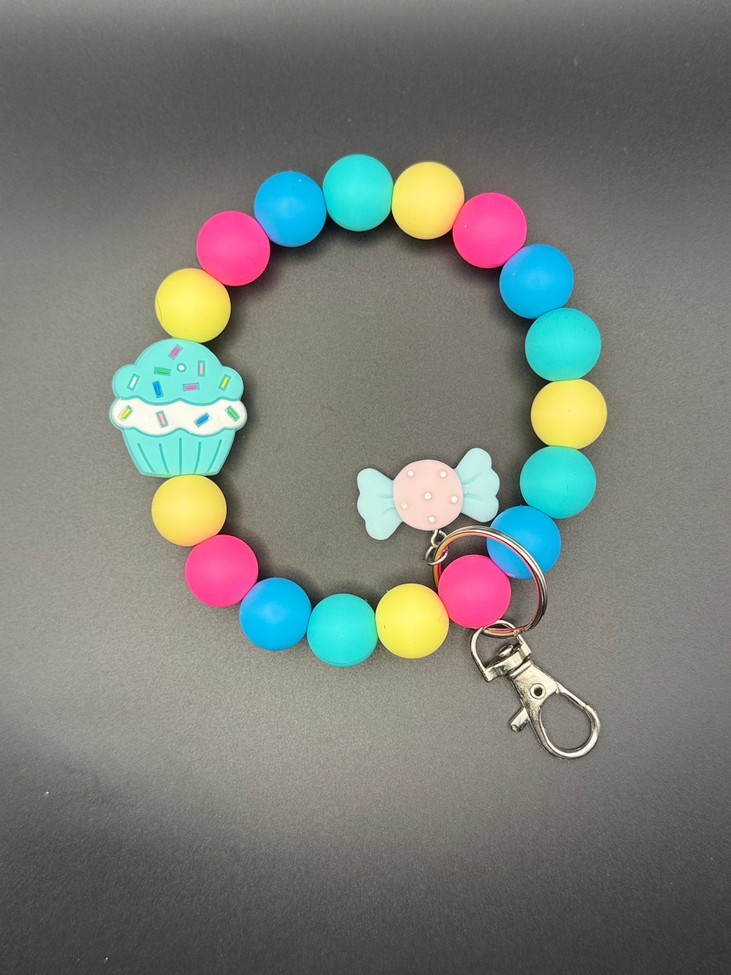 Colorful beaded bracelet with keychain on a gray background