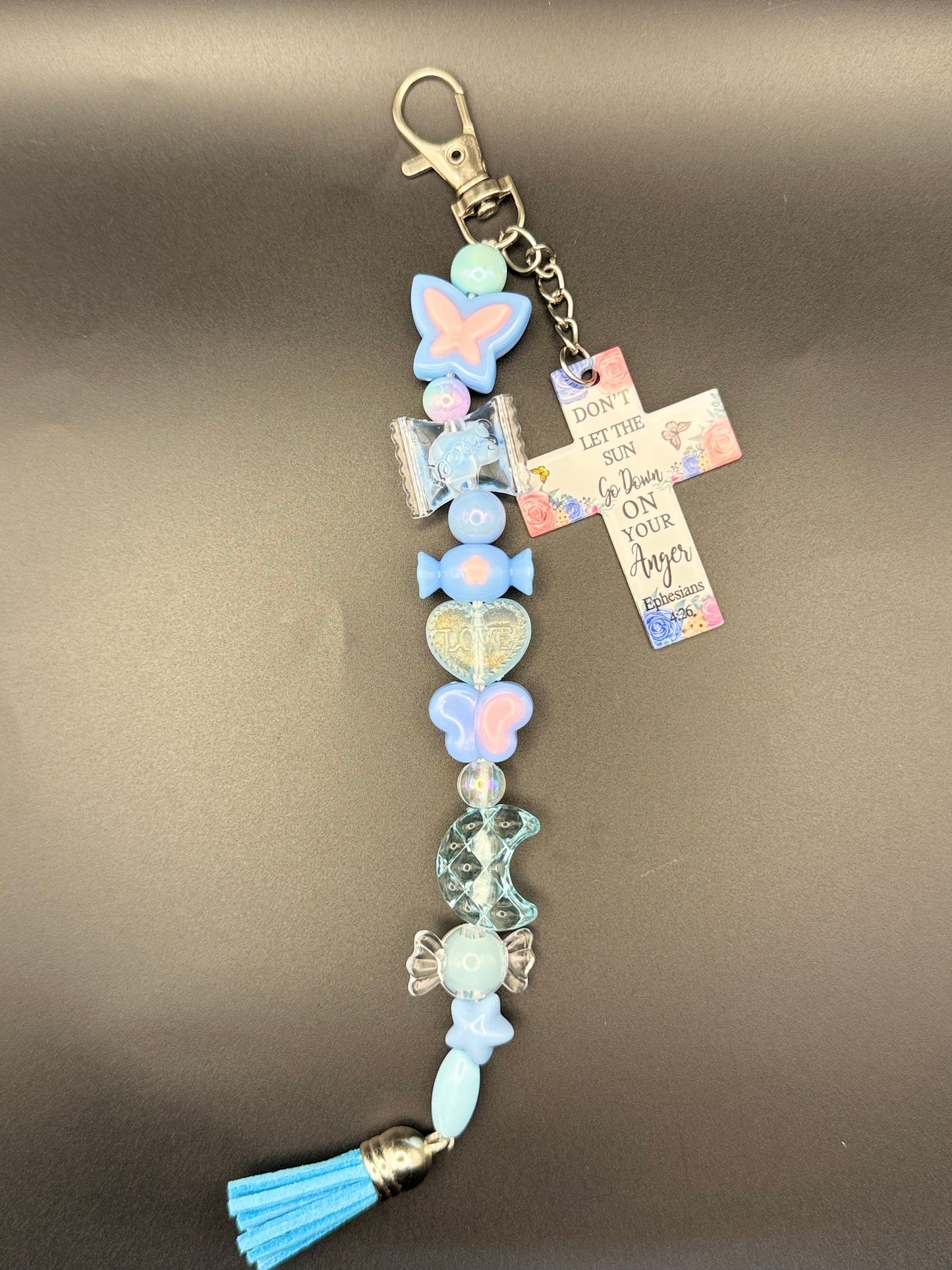 Decorative keychain with pastel colors and religious symbols on a brown background