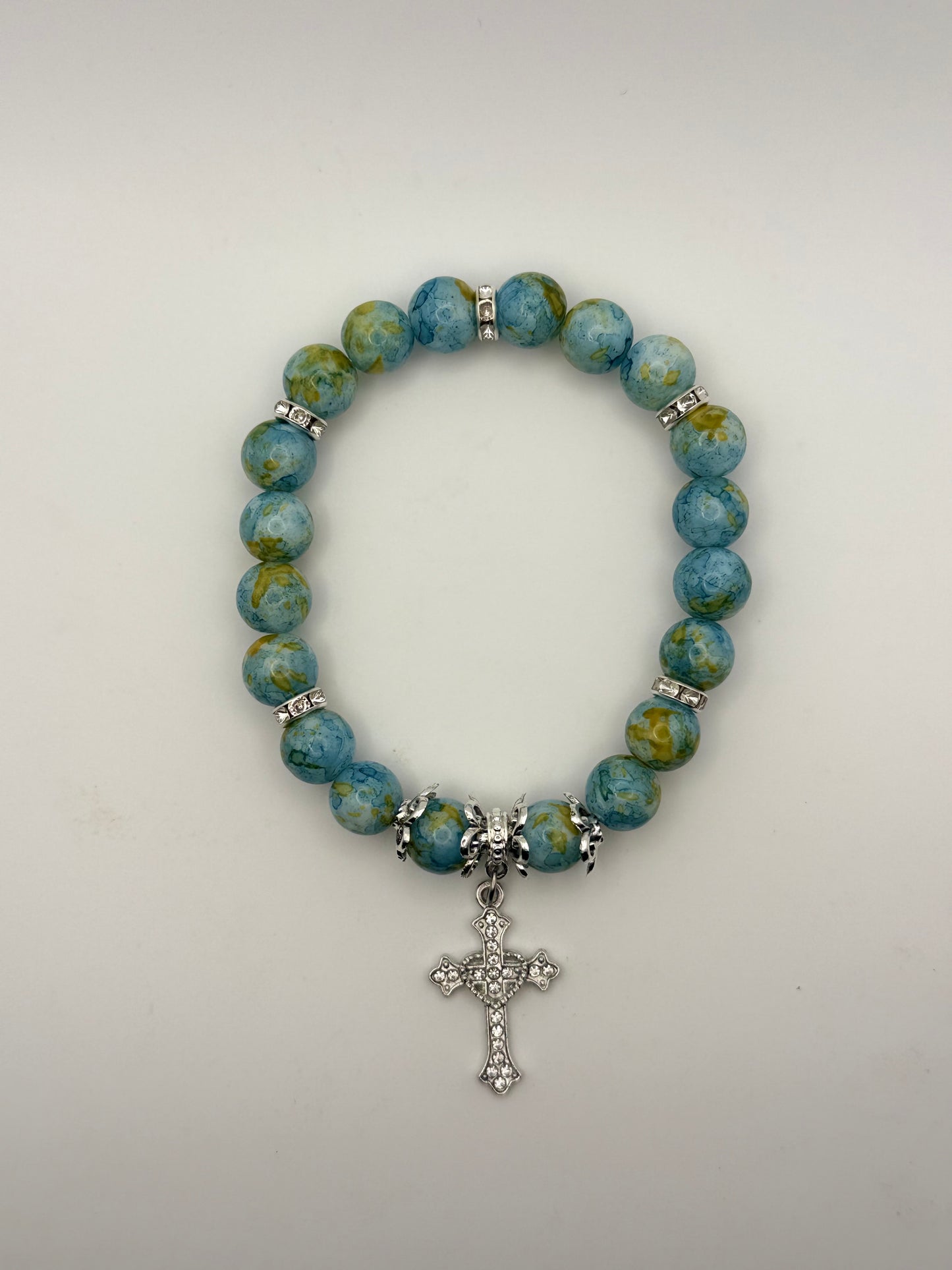 Blue beaded bracelet with a silver cross charm on a white background
