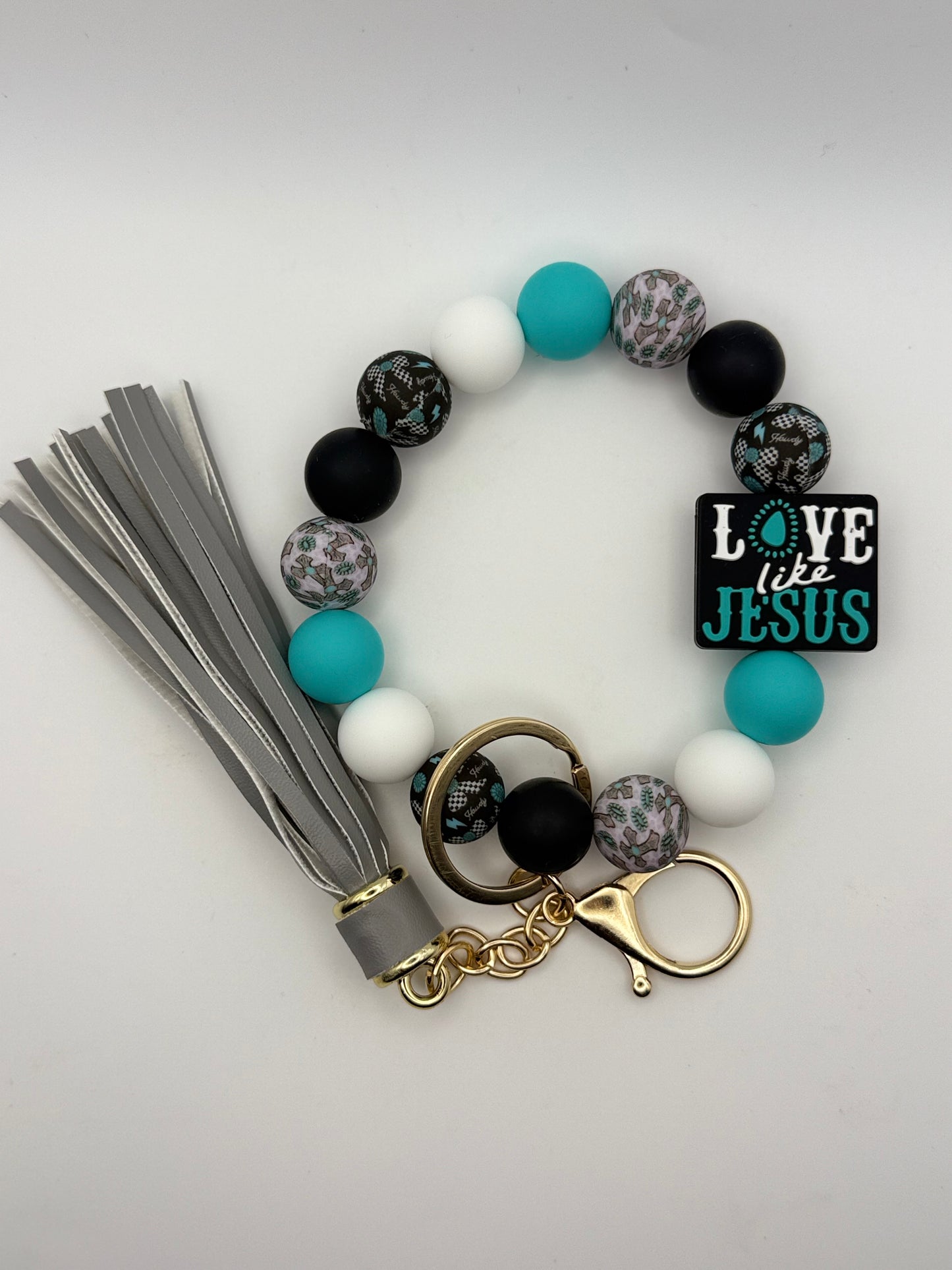 Bracelet with beads, tassel, and 'Love like Jesus' charm on a light gray background