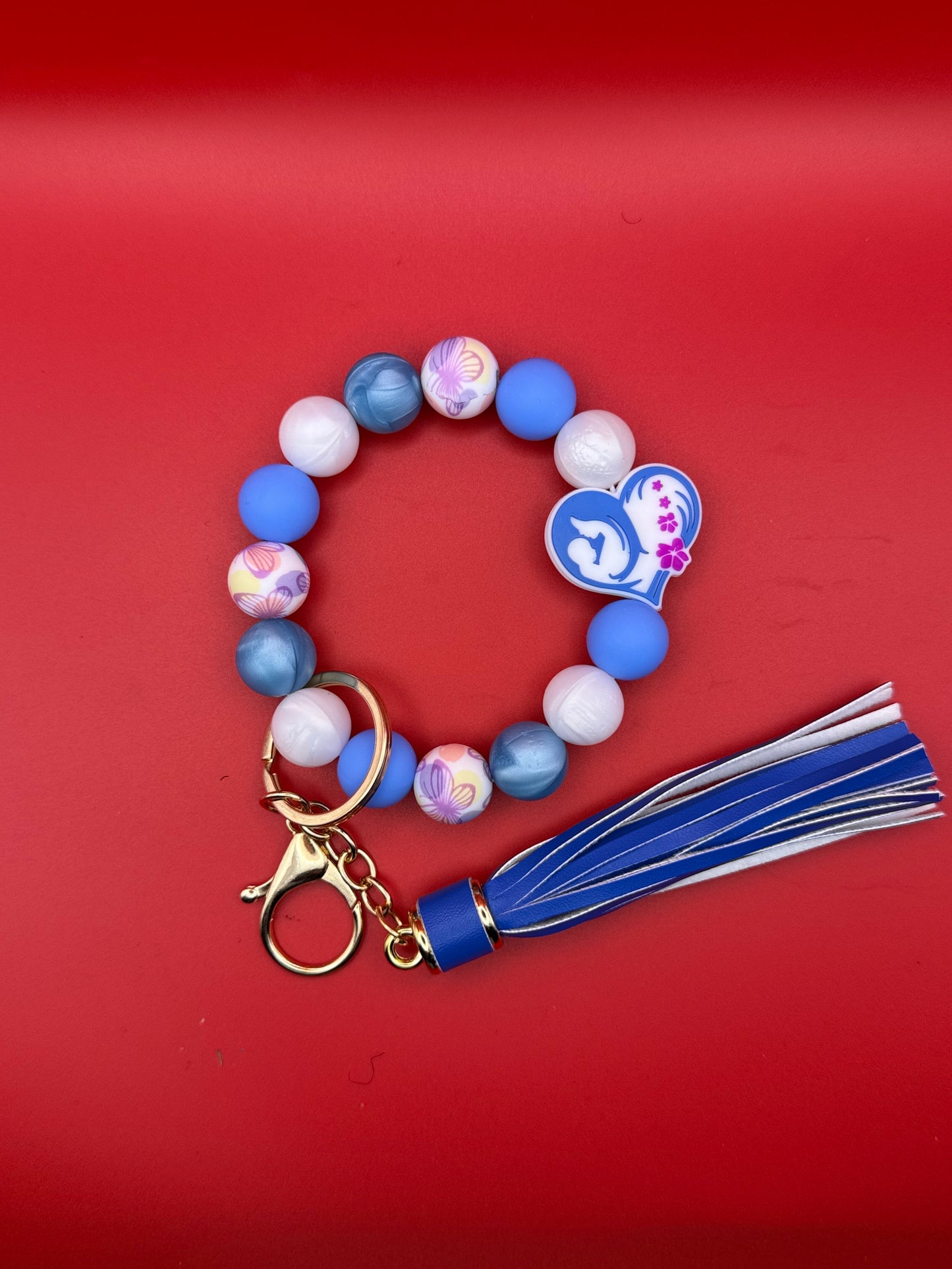 Beaded bracelet with colorful beads and a blue tassel keychain on a red background