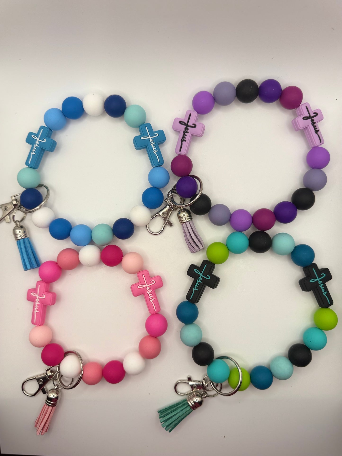 Colorful beaded bracelets with cross charms and keychains on a white background