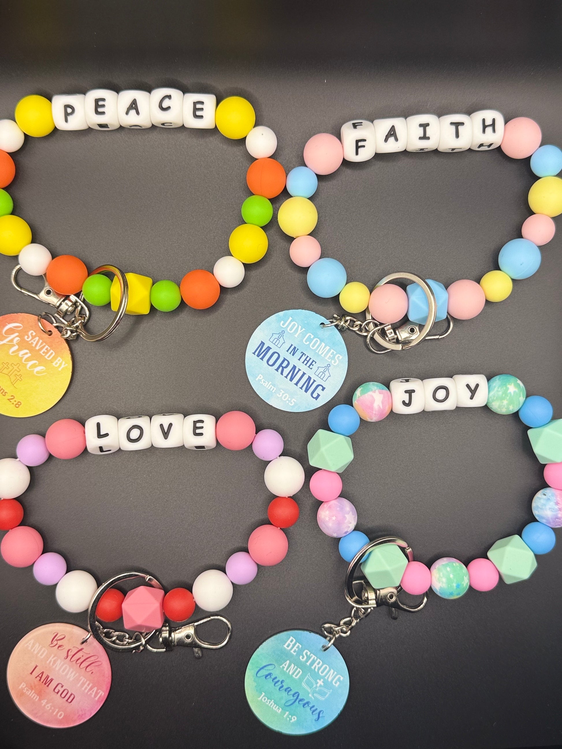Colorful beaded bracelets with inspirational charms on a dark background