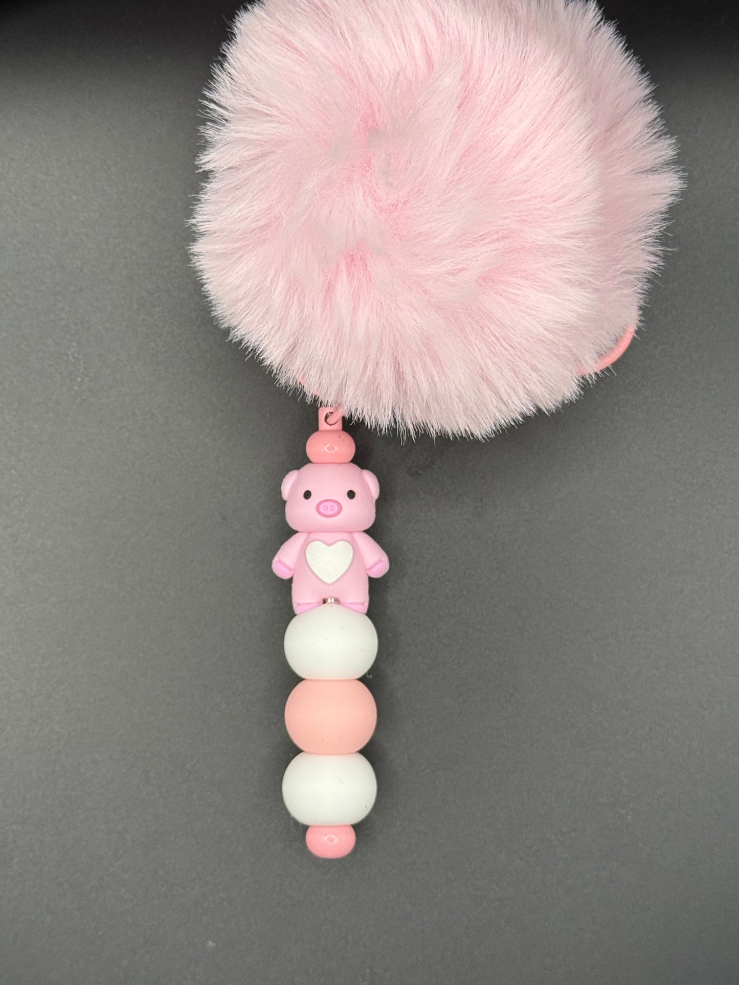 Pink fluffy object with a string of colorful beads on a gray background