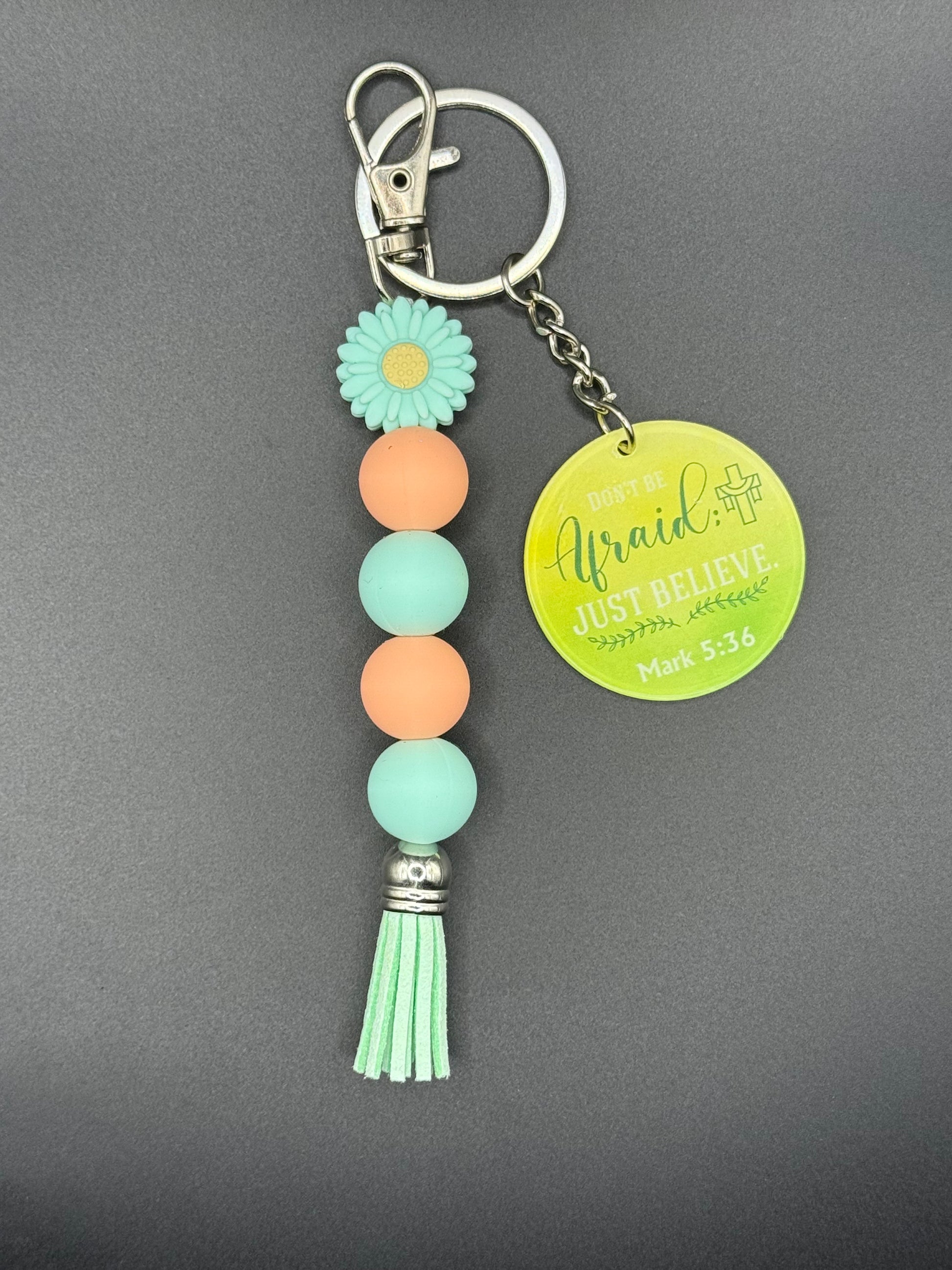 Green Flower Keychain with beads and tassel on a gray background