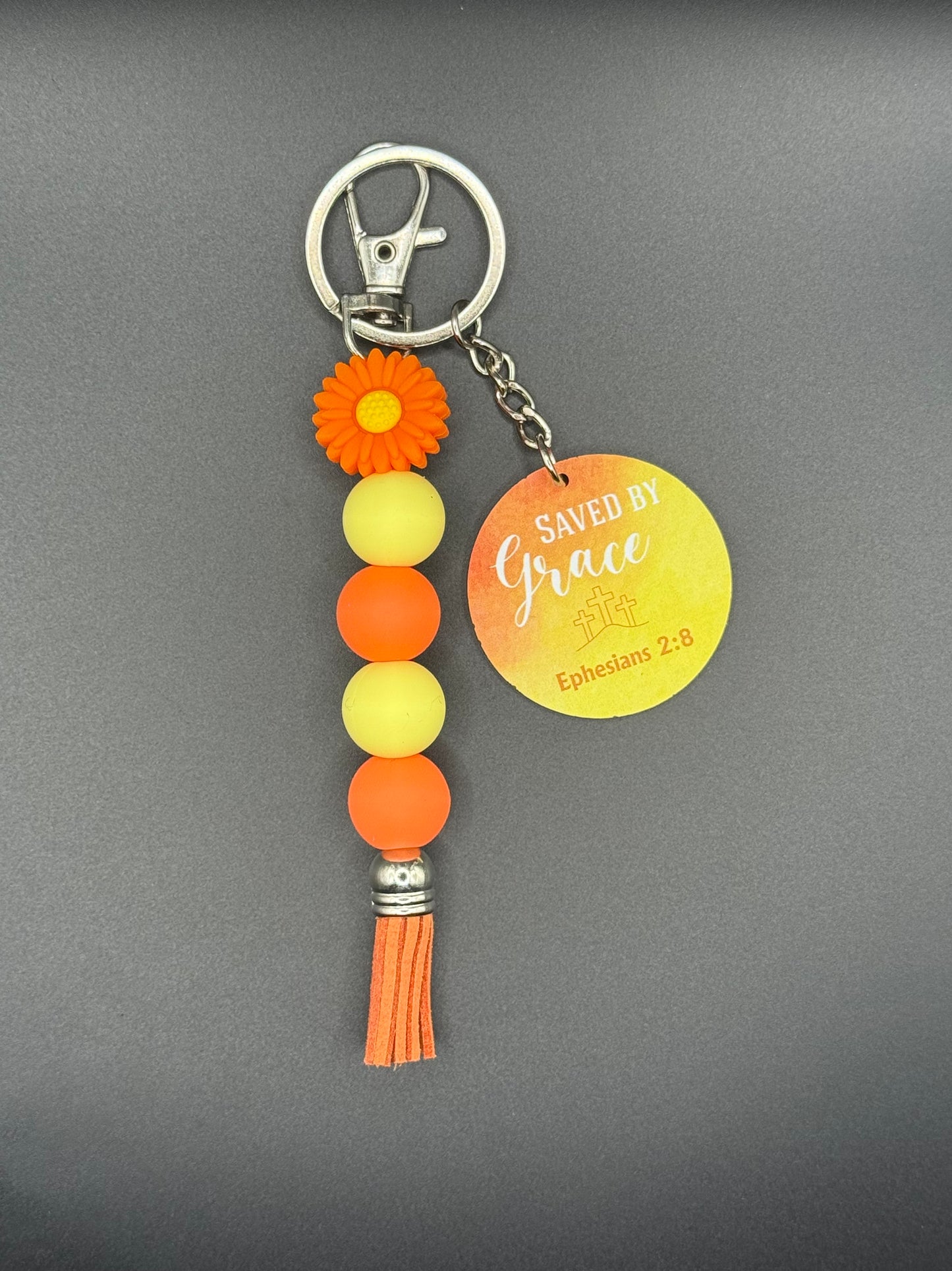 Orange Flower Keychain with colorful beads and tassel on a gray background