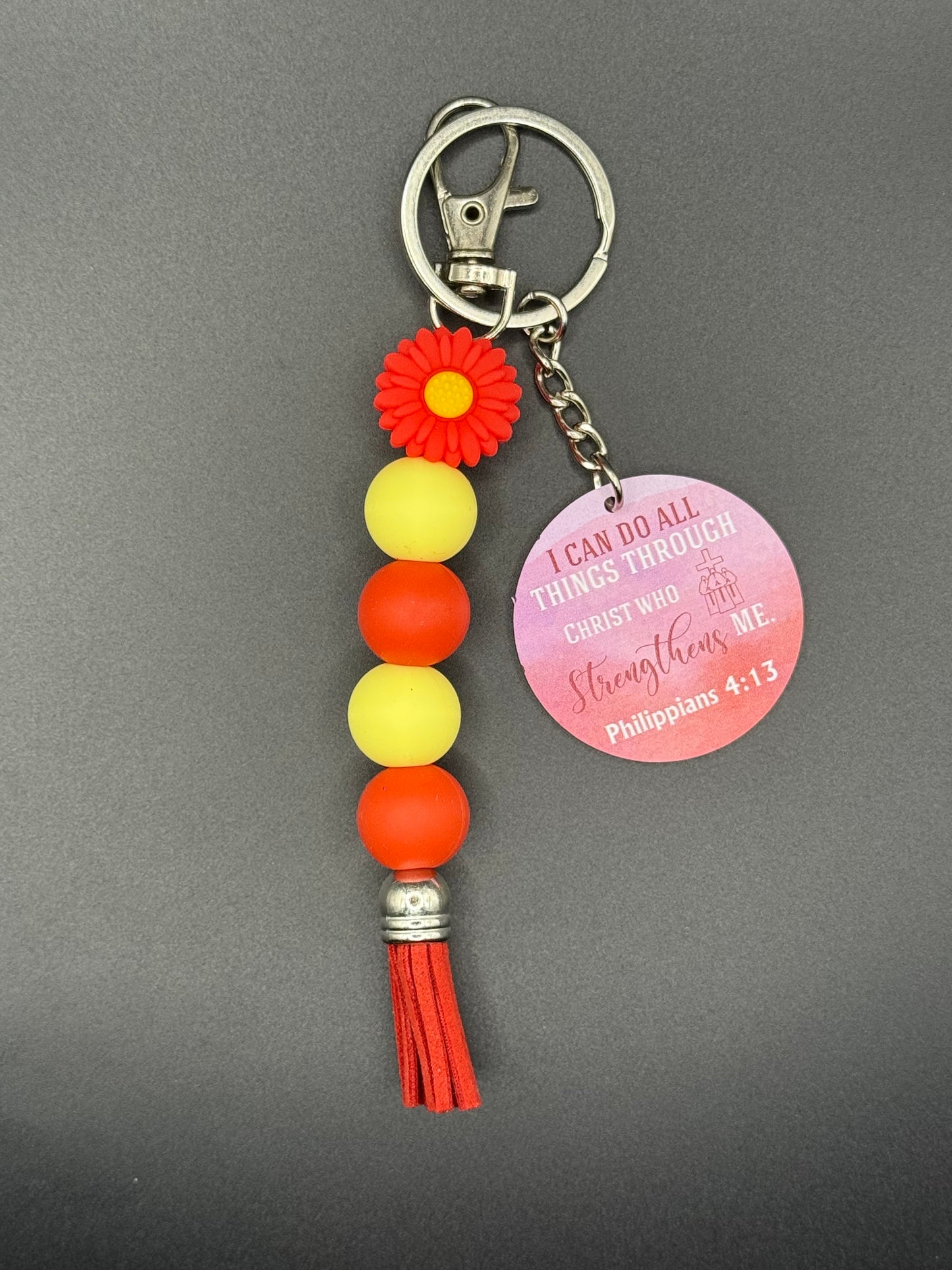Red Flower Keychain with colorful beads and a tassel on a gray background