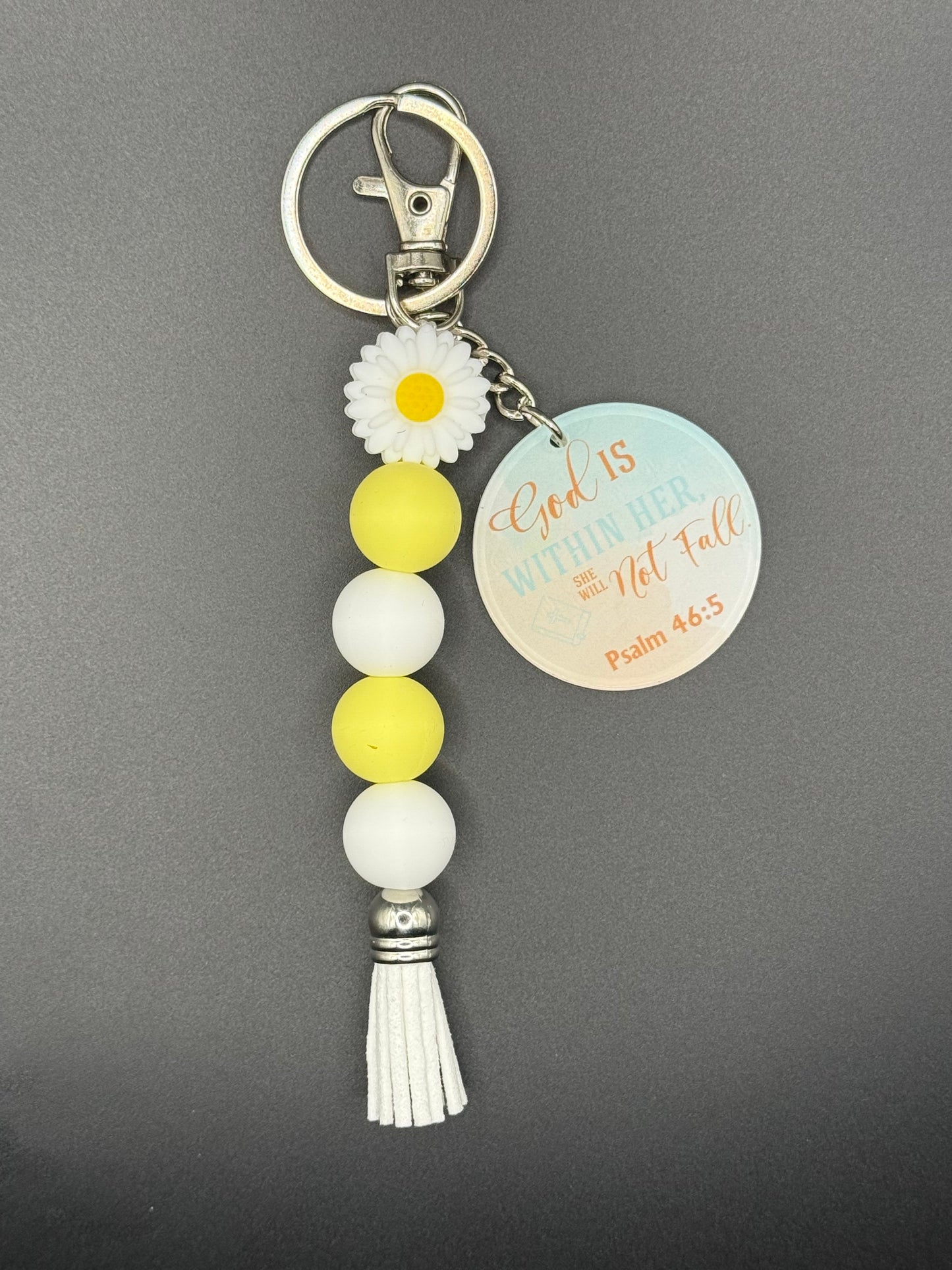 White Flower Keychain with beads and a tassel on a gray background