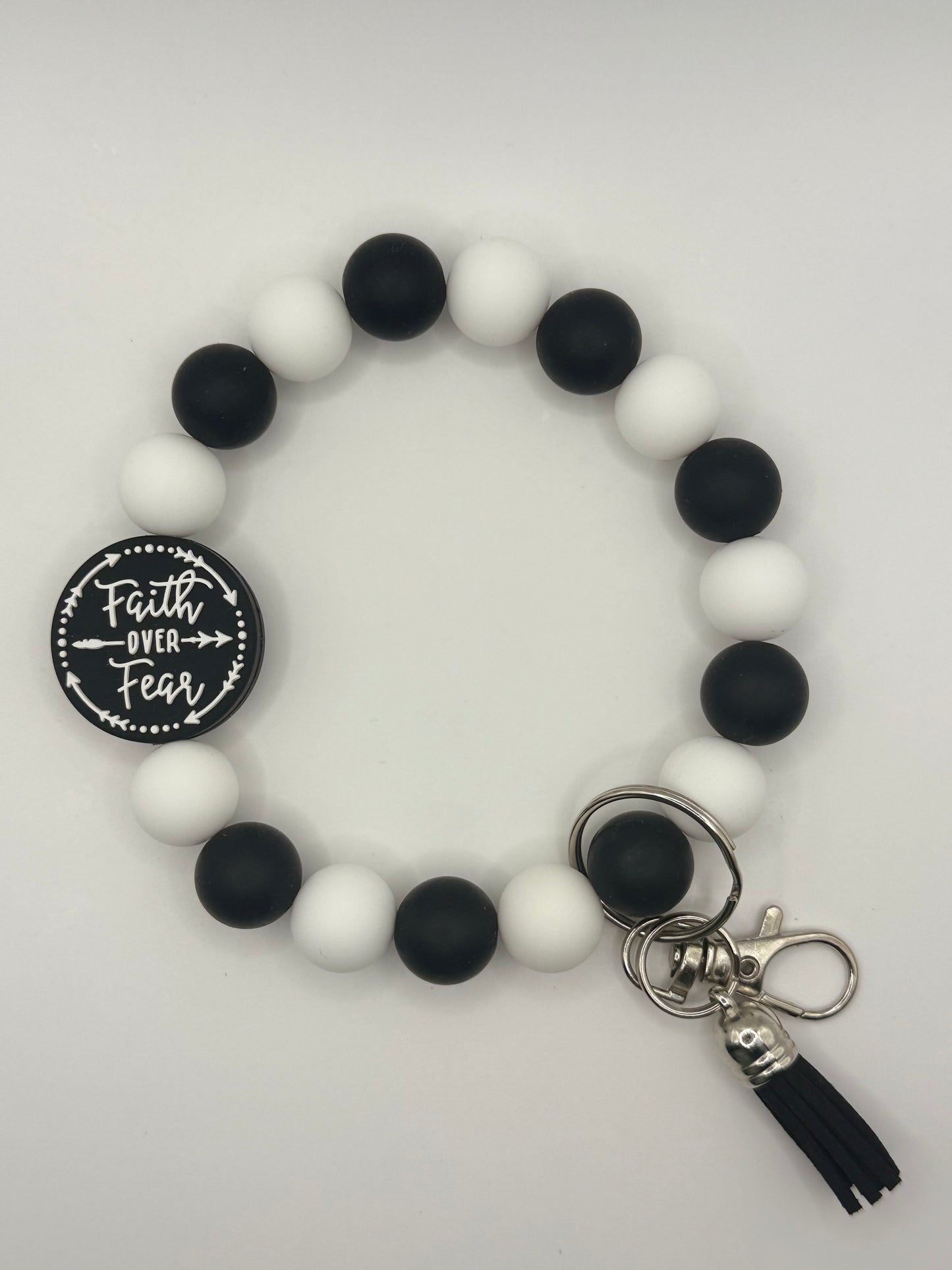 Black and white beaded bracelet with a keychain and tassel on a light gray background