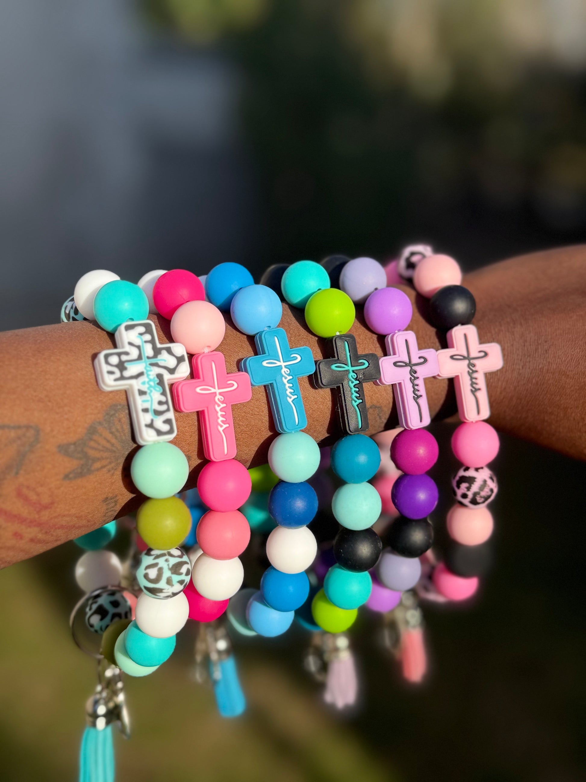 Colorful beaded bracelets with cross charms on a wrist against a blurred background