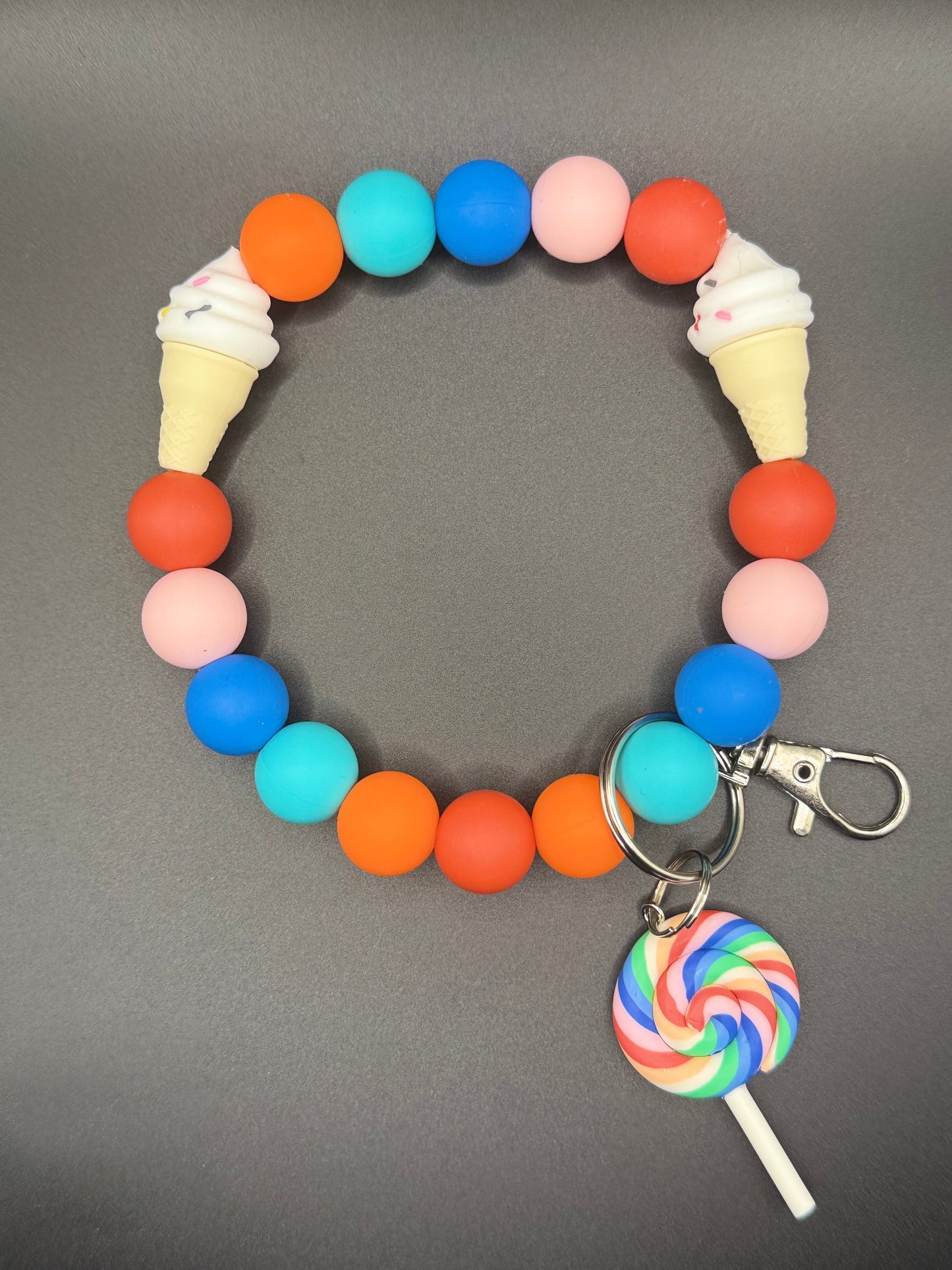 Colorful bracelet with ice cream cone and lollipop charms on a gray background