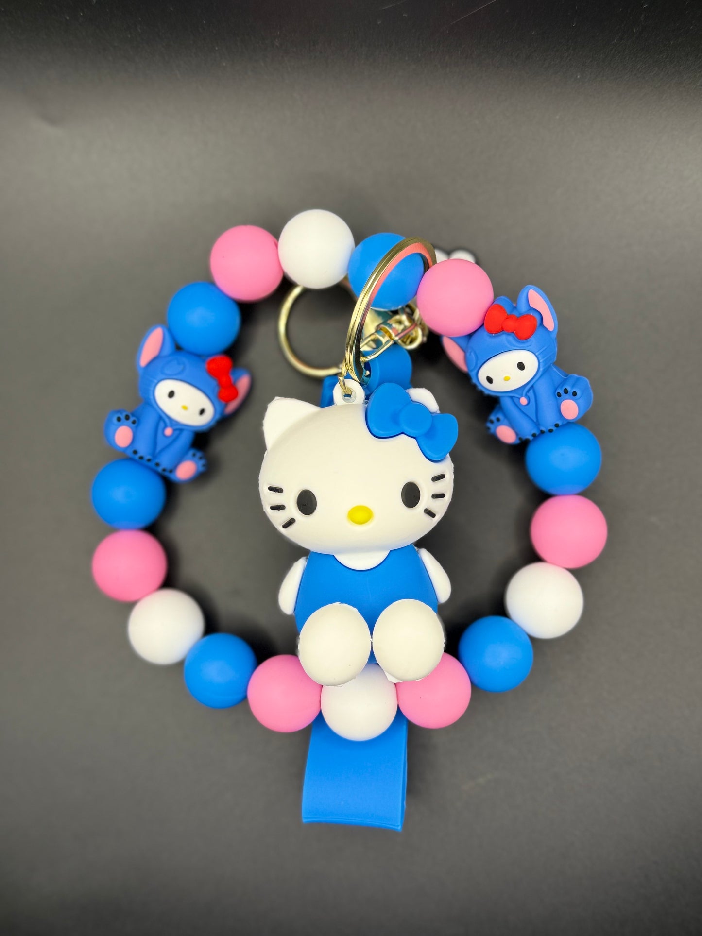 Colorful bracelet with a Kitty character and small blue characters on a dark background