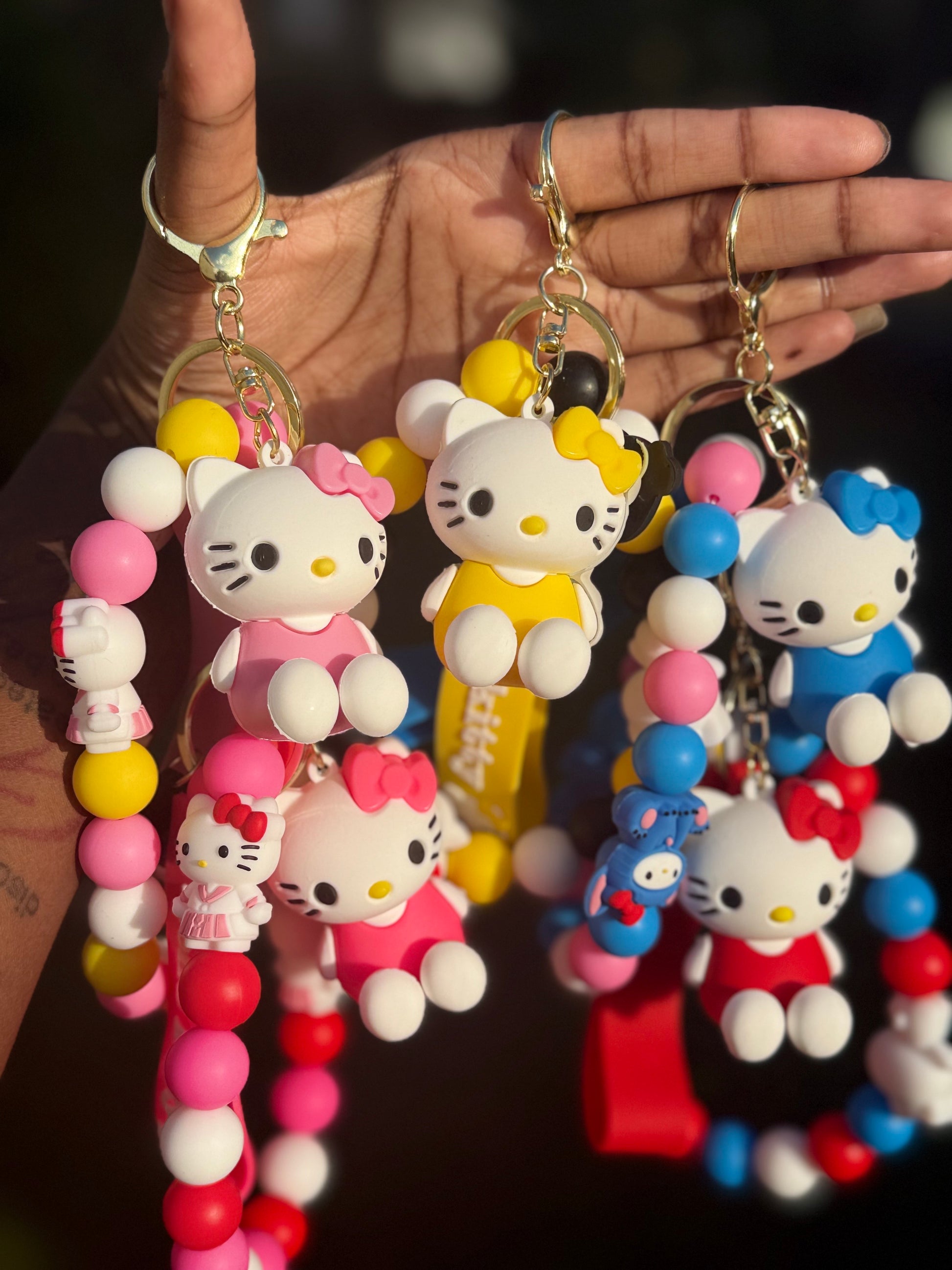 Colorful keychains with Kitty figures held by a hand.