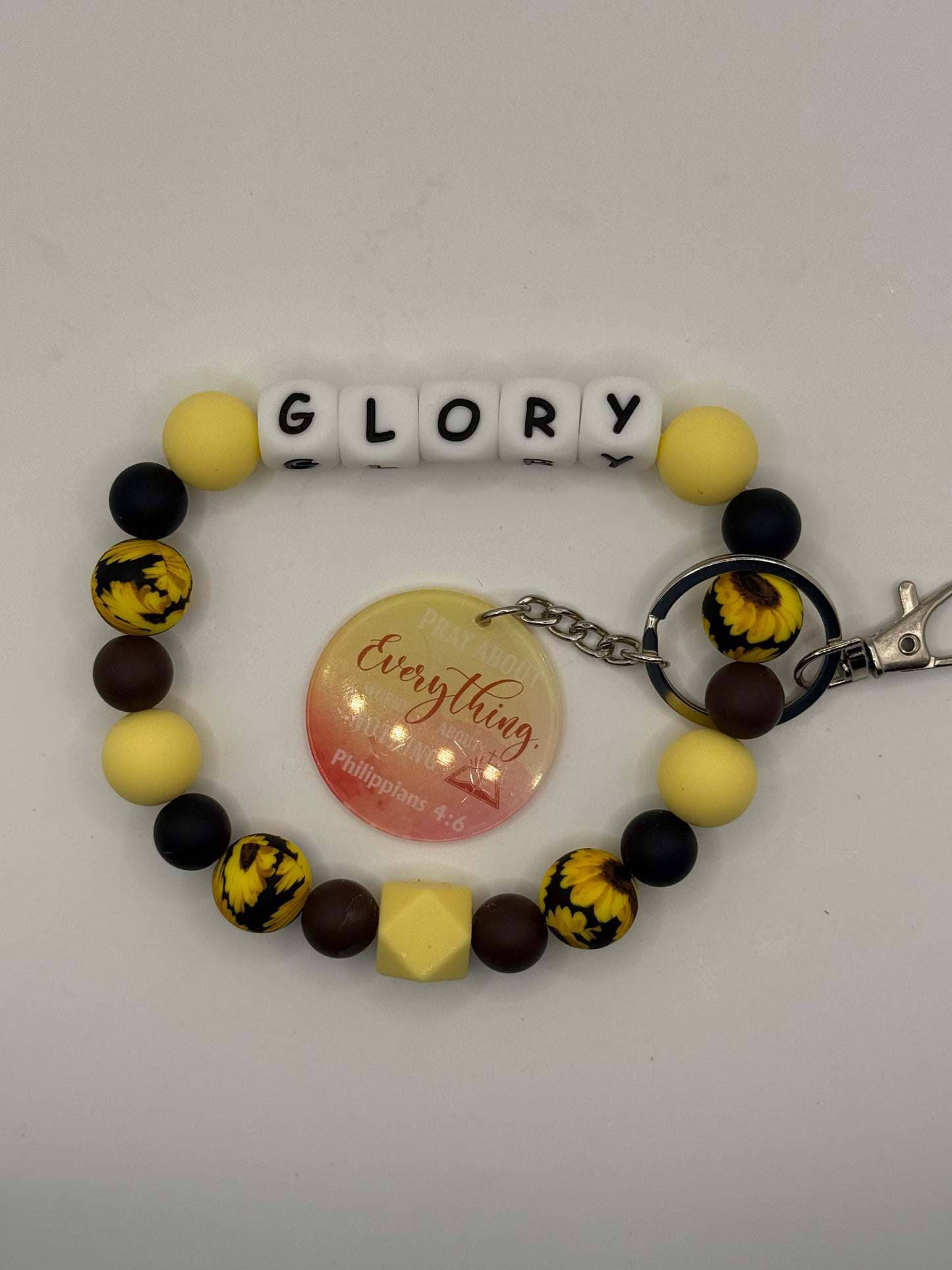 Colorful beaded bracelet with letter beads spelling 'GLORY' on a gray background