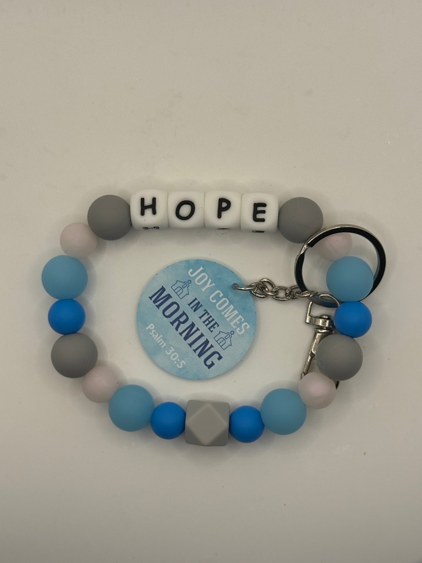 Colorful beaded bracelet with letter beads spelling 'HOPE' on a gray background