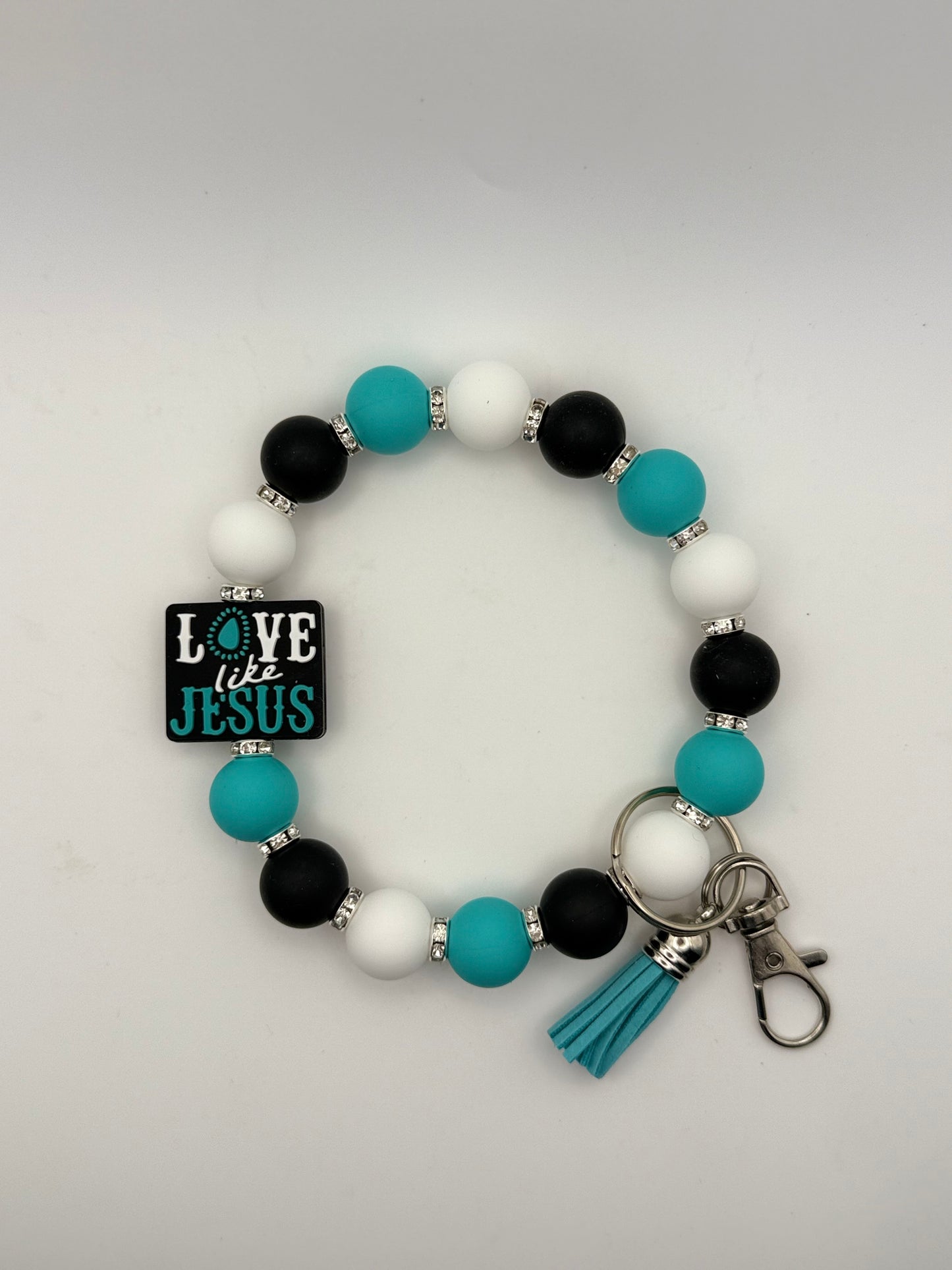 Beaded bracelet with 'Love is Jesus' charm on a gray background