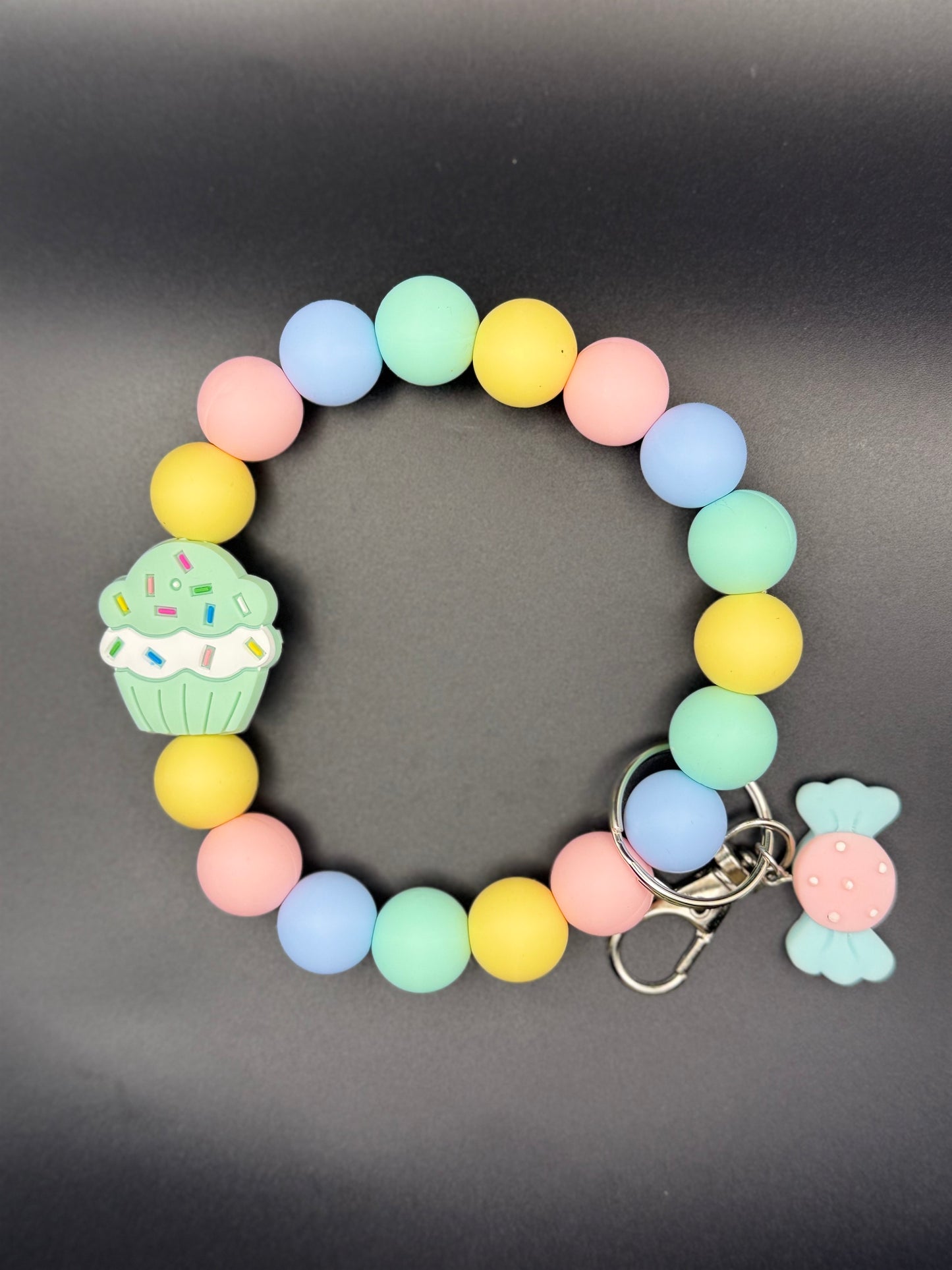 Colorful beaded bracelet with keychain on a gray background