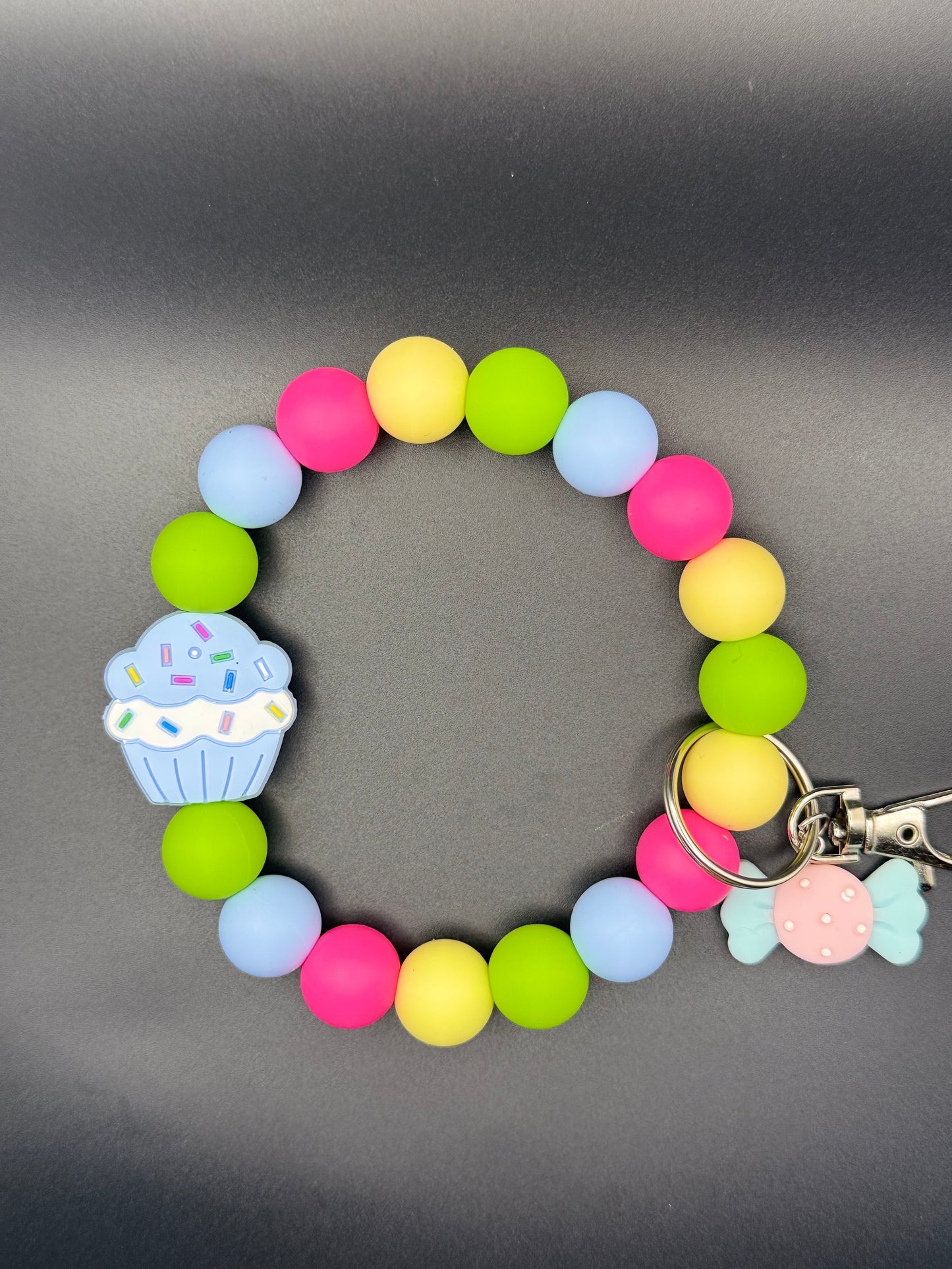 Colorful beaded bracelet with a cupcake charm on a gray background