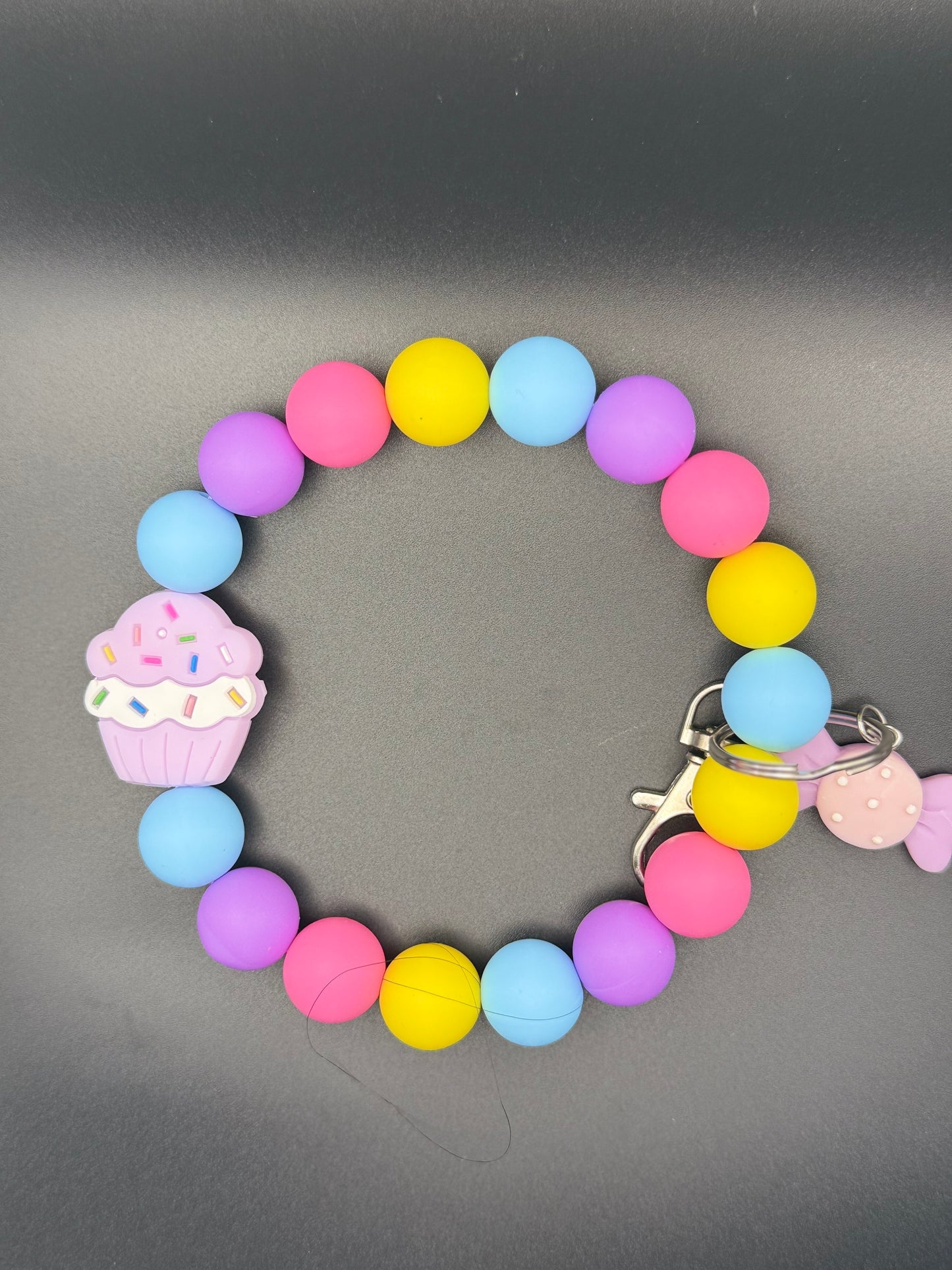 Colorful beaded bracelet with a cupcake charm on a gray background