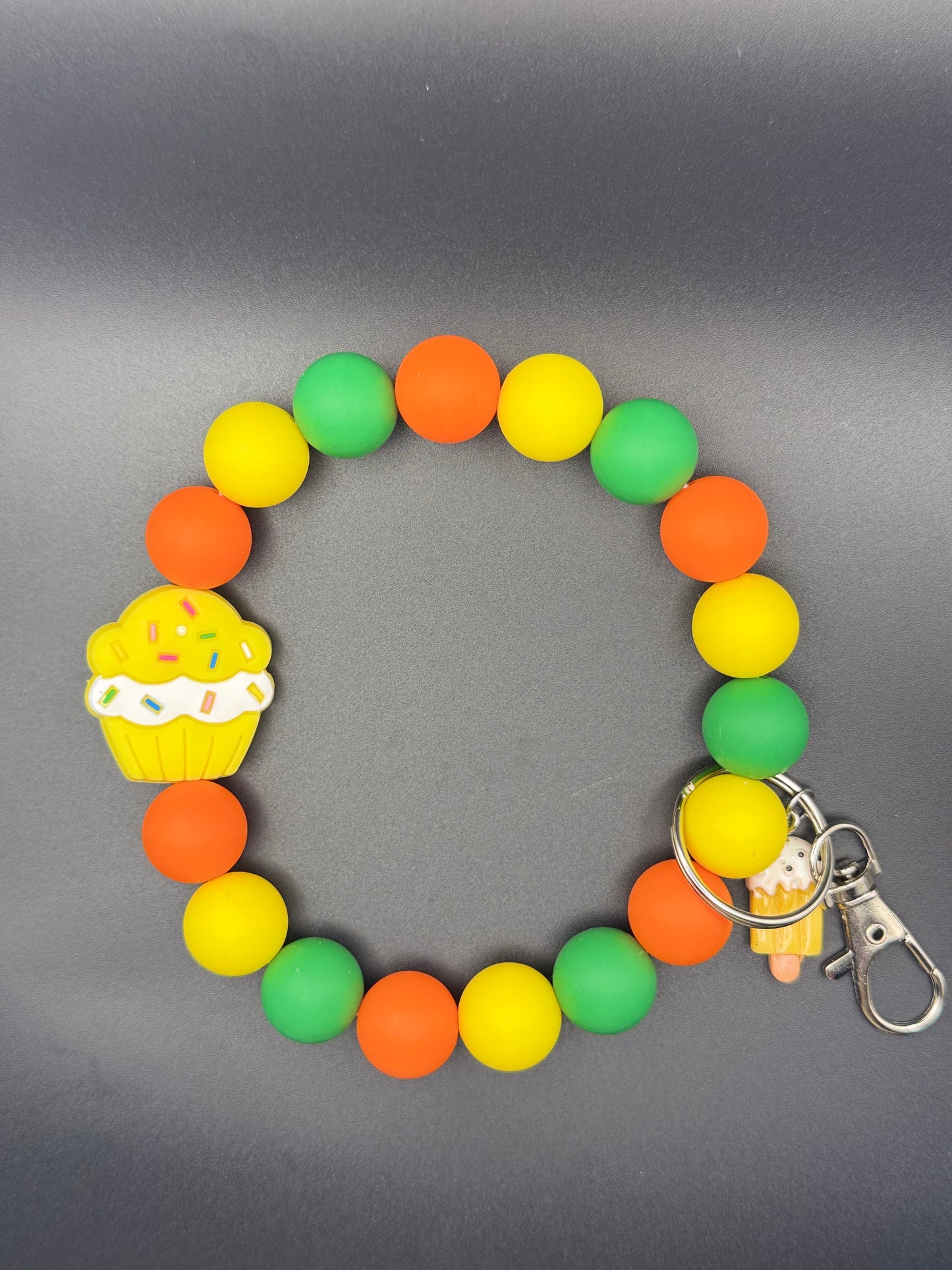 Colorful beaded bracelet with cupcake charm on a gray background