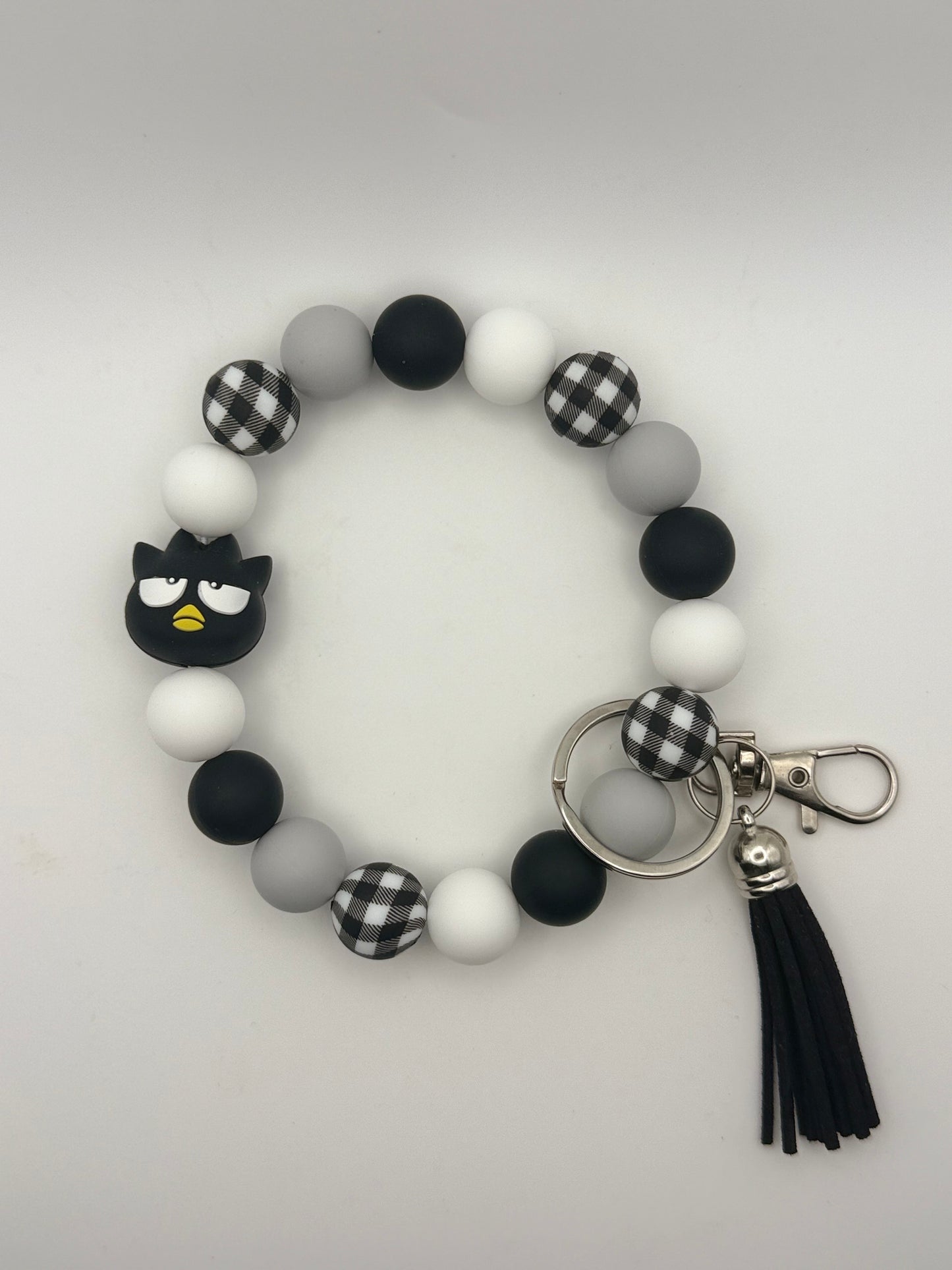 Bracelet with black and white checkered accents, tassel, and keychain on a light gray background