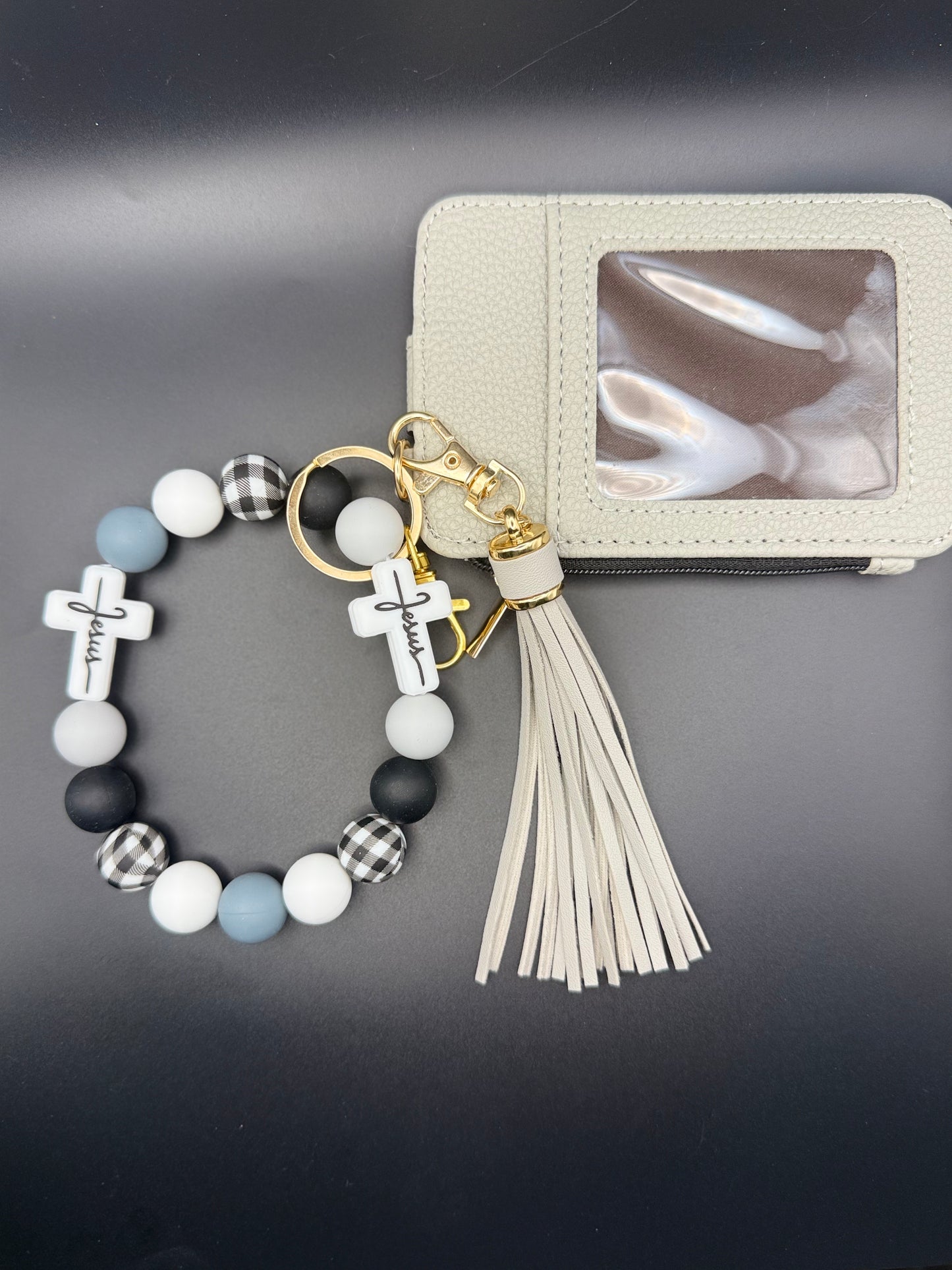 Bracelet with keychain and tassel next to a small pouch on a dark background