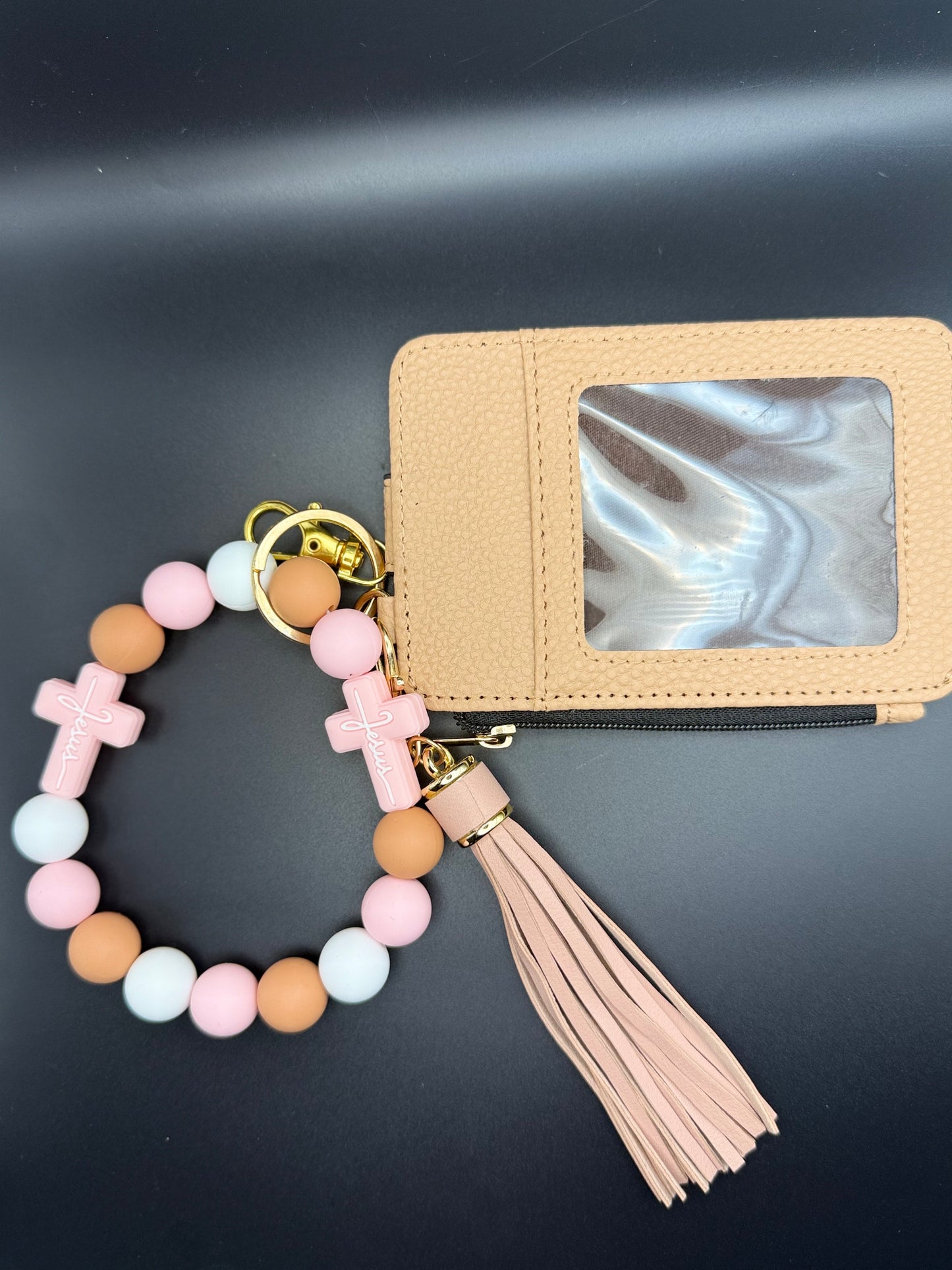 Beaded keychain with tassel attached to a beige cardholder on a dark background