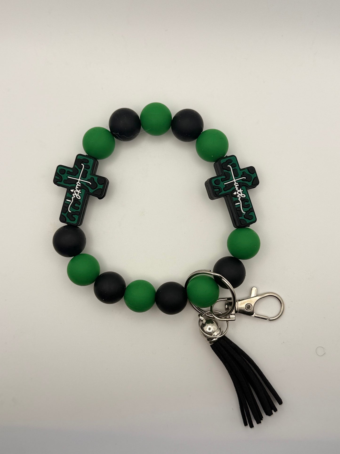 Bracelet with green and black beads and cross charms on a light gray background