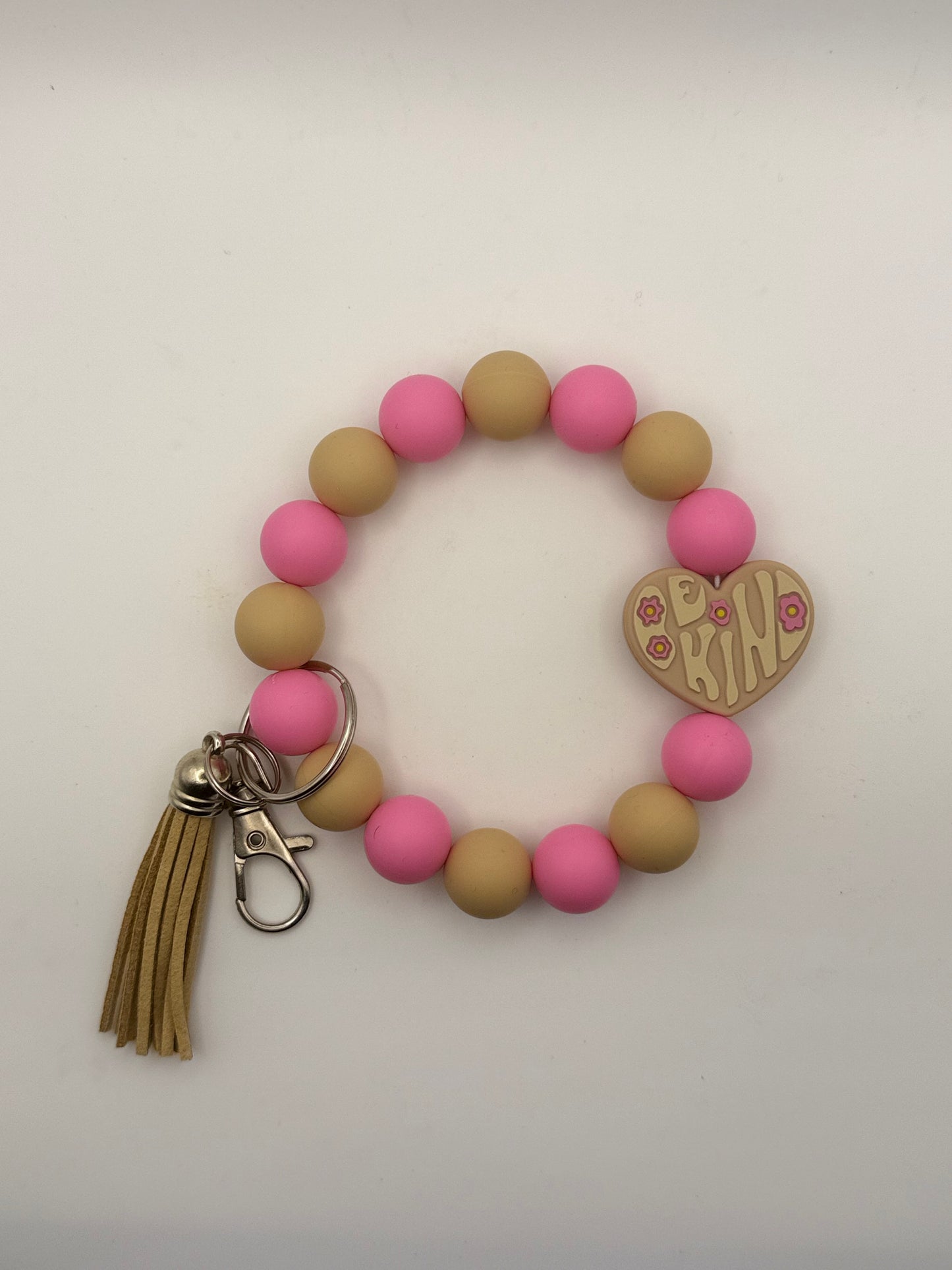 Bracelet with pink and beige beads, tassel, and heart-shaped keychain charm on a white background