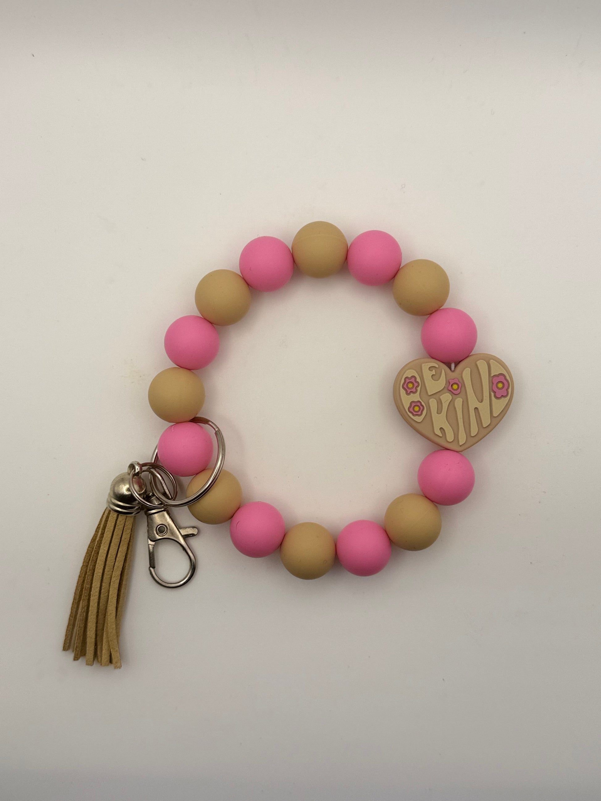 Bracelet with pink and beige beads, tassel, and heart-shaped keychain charm on a white background