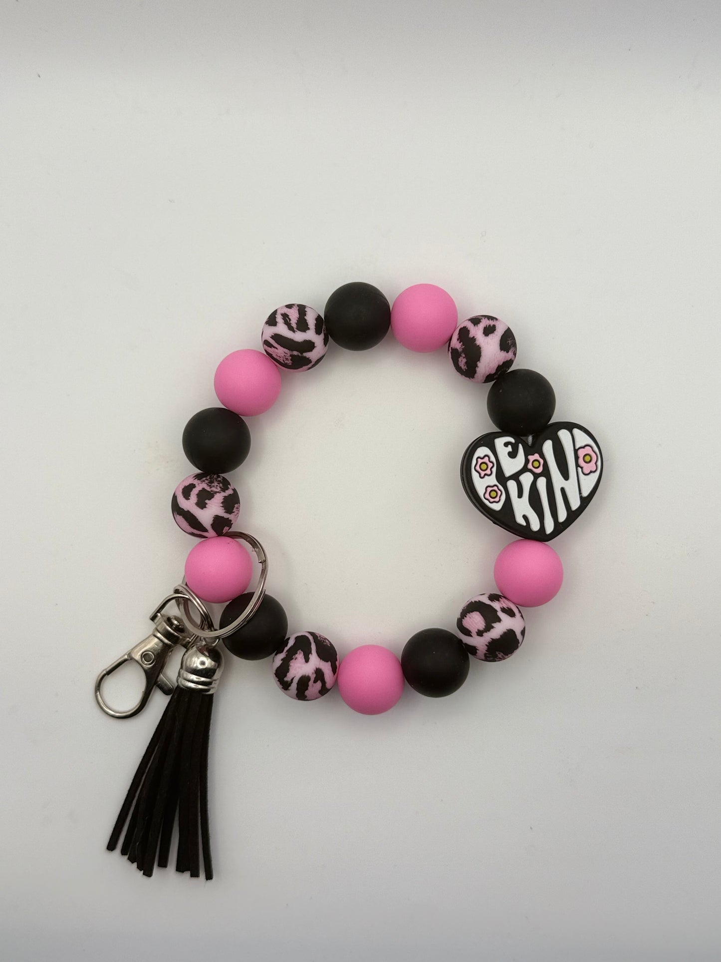 Bracelet with pink and black beads and a 'Be Kind' charm on a white background