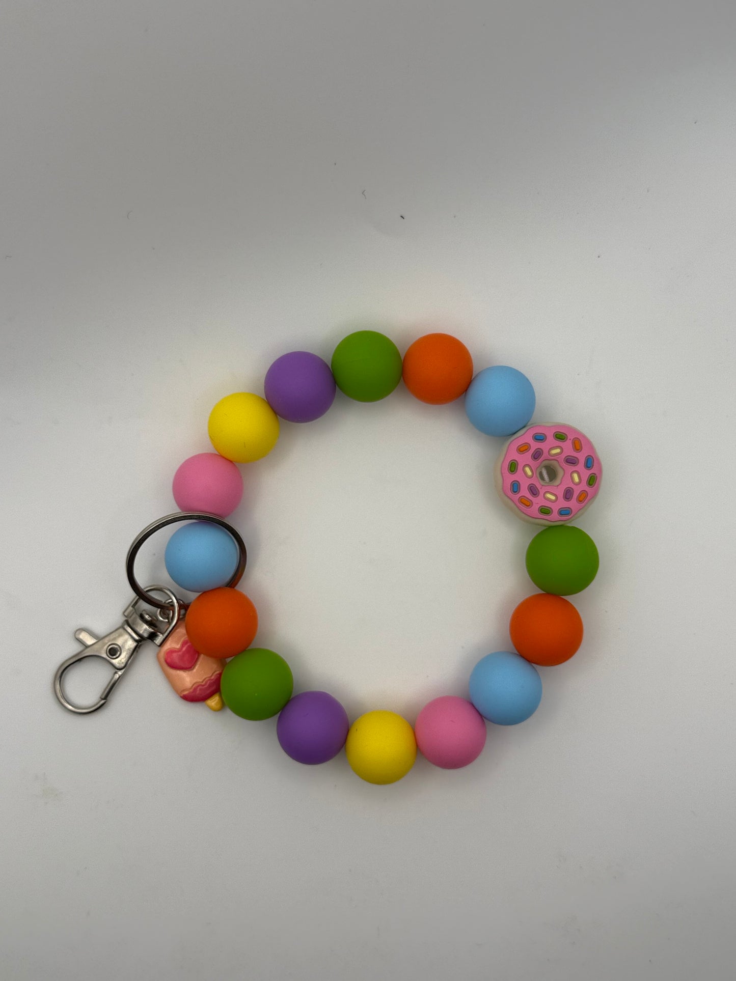 Colorful beaded bracelet keychain with a donut charm on a white background