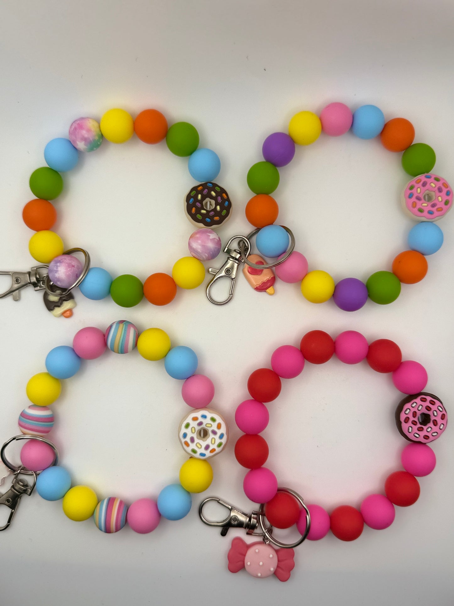 Colorful beaded bracelets with donut charms on a white background