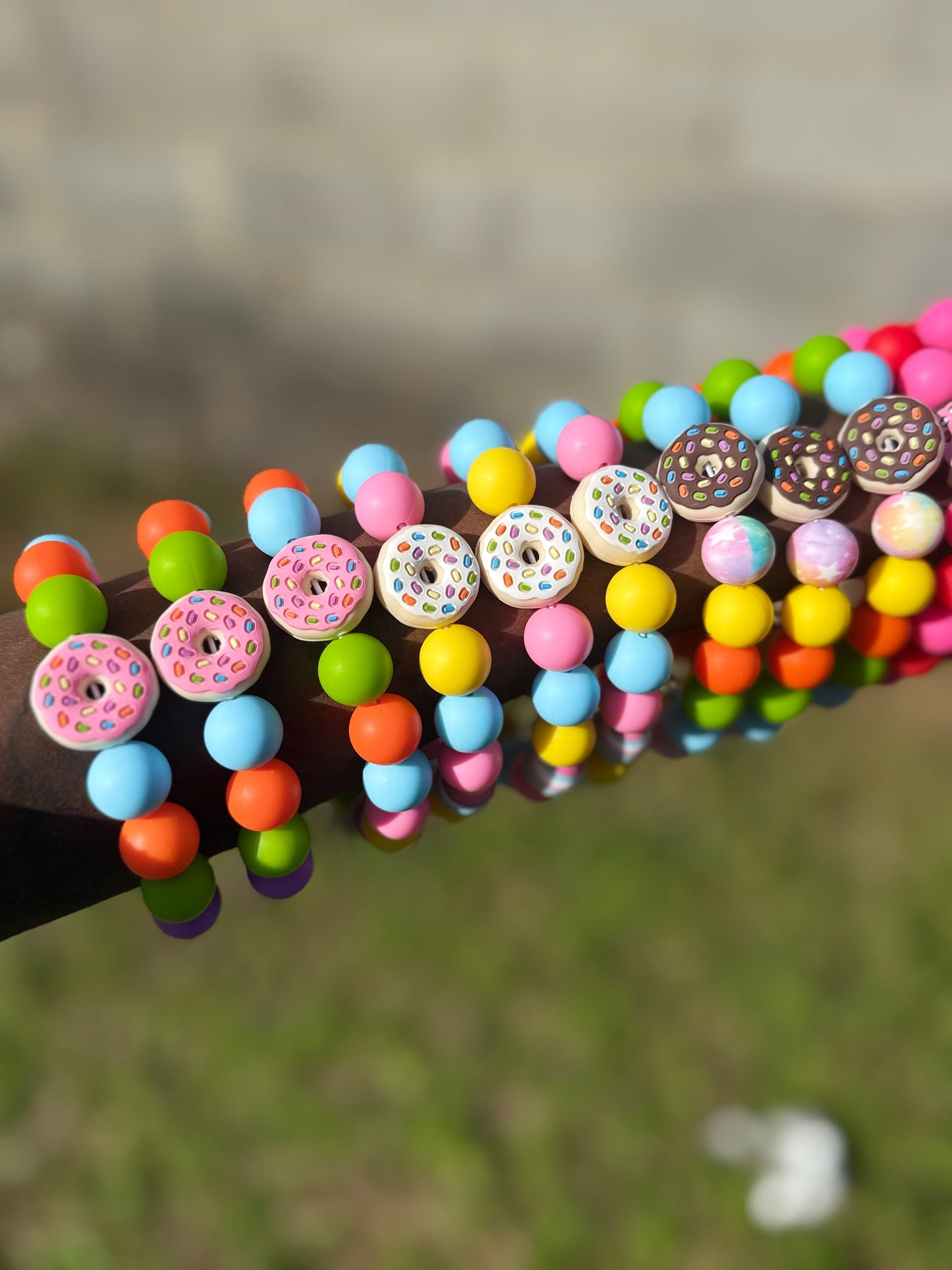Colorful beaded bracelet with donut-shaped beads on a blurred grass background
