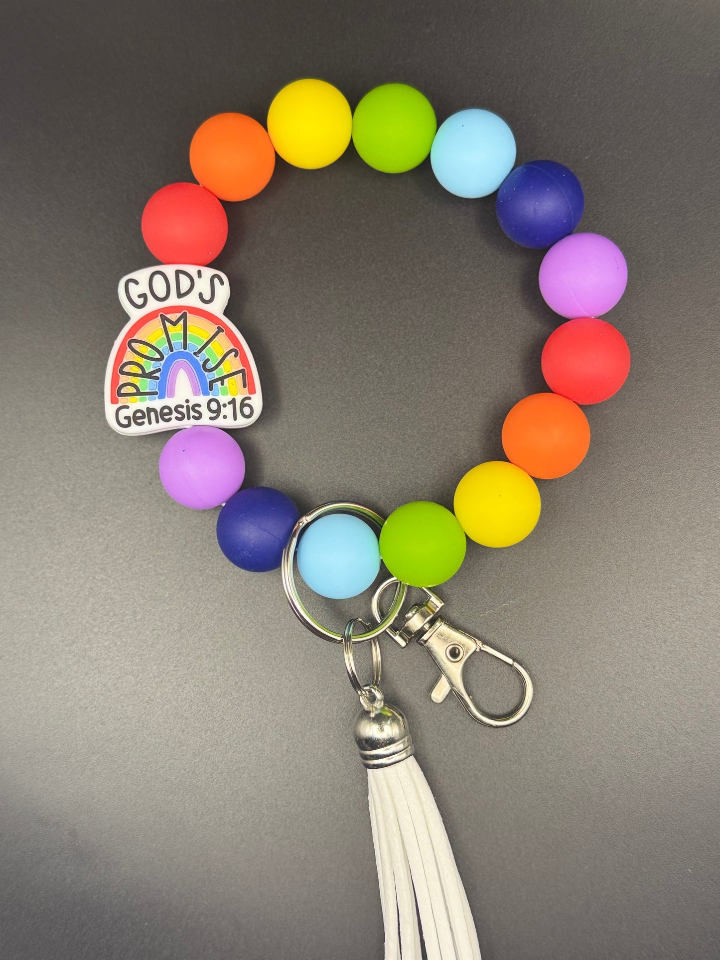 Colorful beaded keychain with a rainbow design and 'God's Genesis 9:16' tag on a gray background