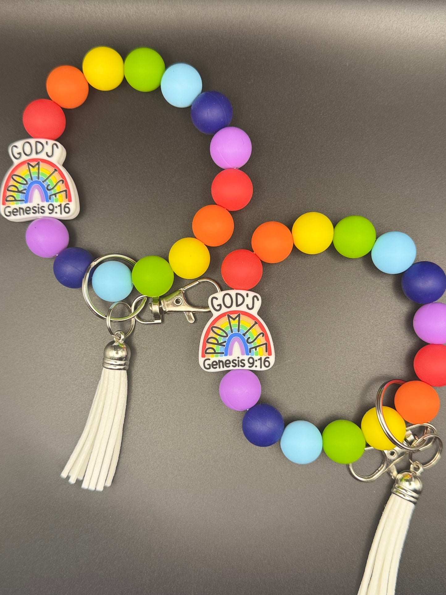 Colorful beaded bracelet with rainbow charm and tassel on a gray background