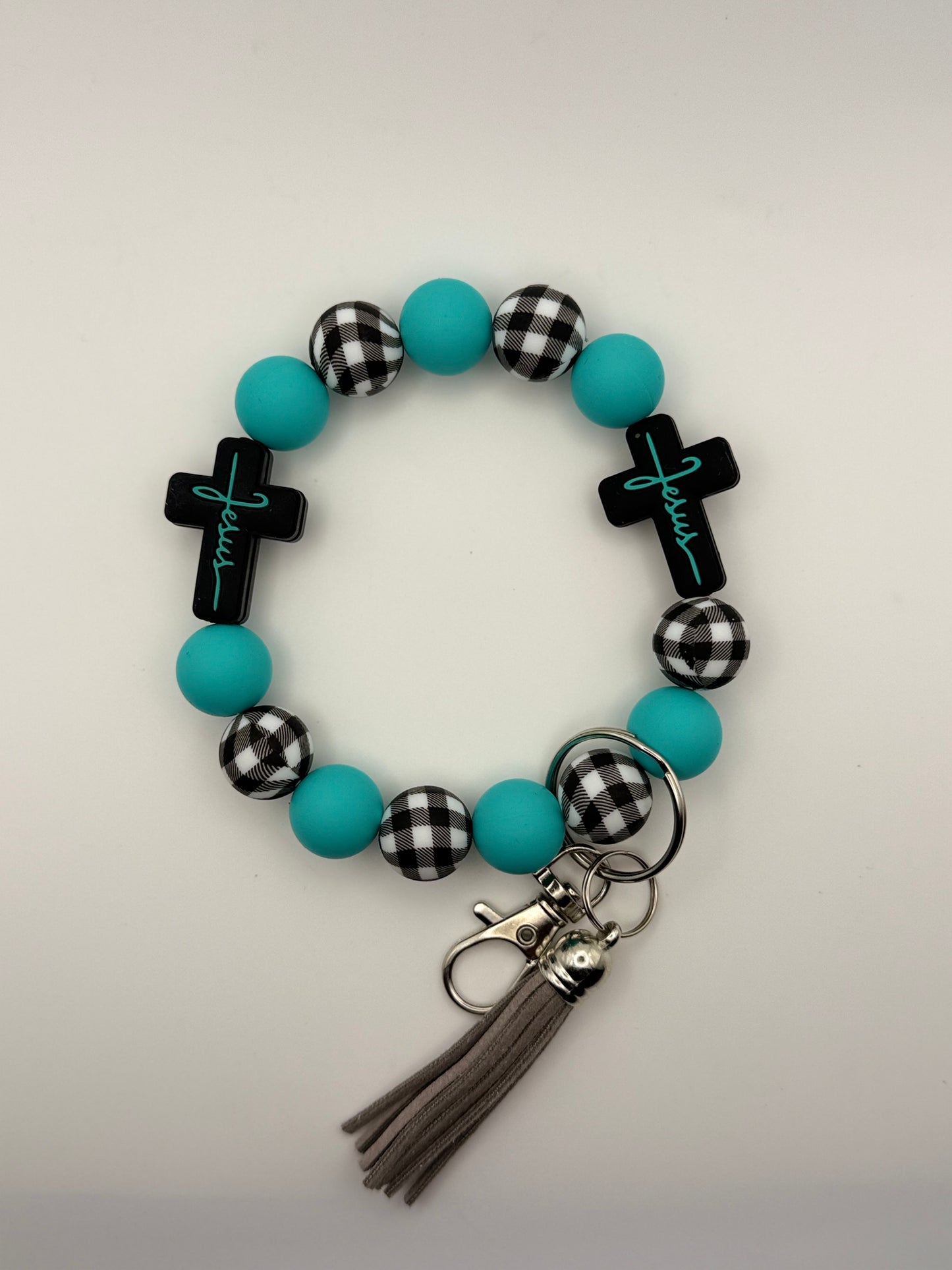 Bracelet with turquoise beads, black and white checkered accents, and tassel on a light gray background
