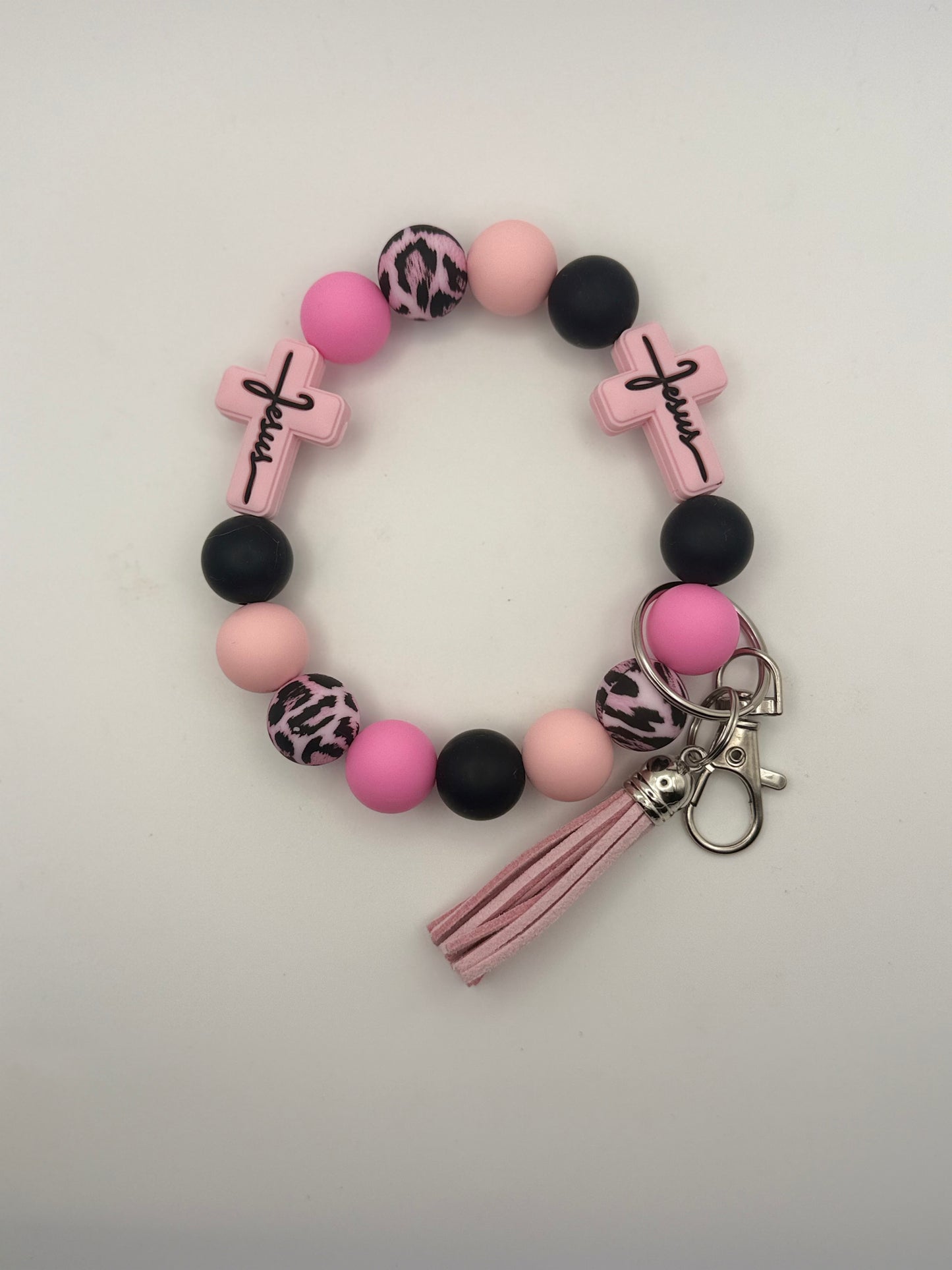Bracelet with pink and black beads and cross charms on a light gray background