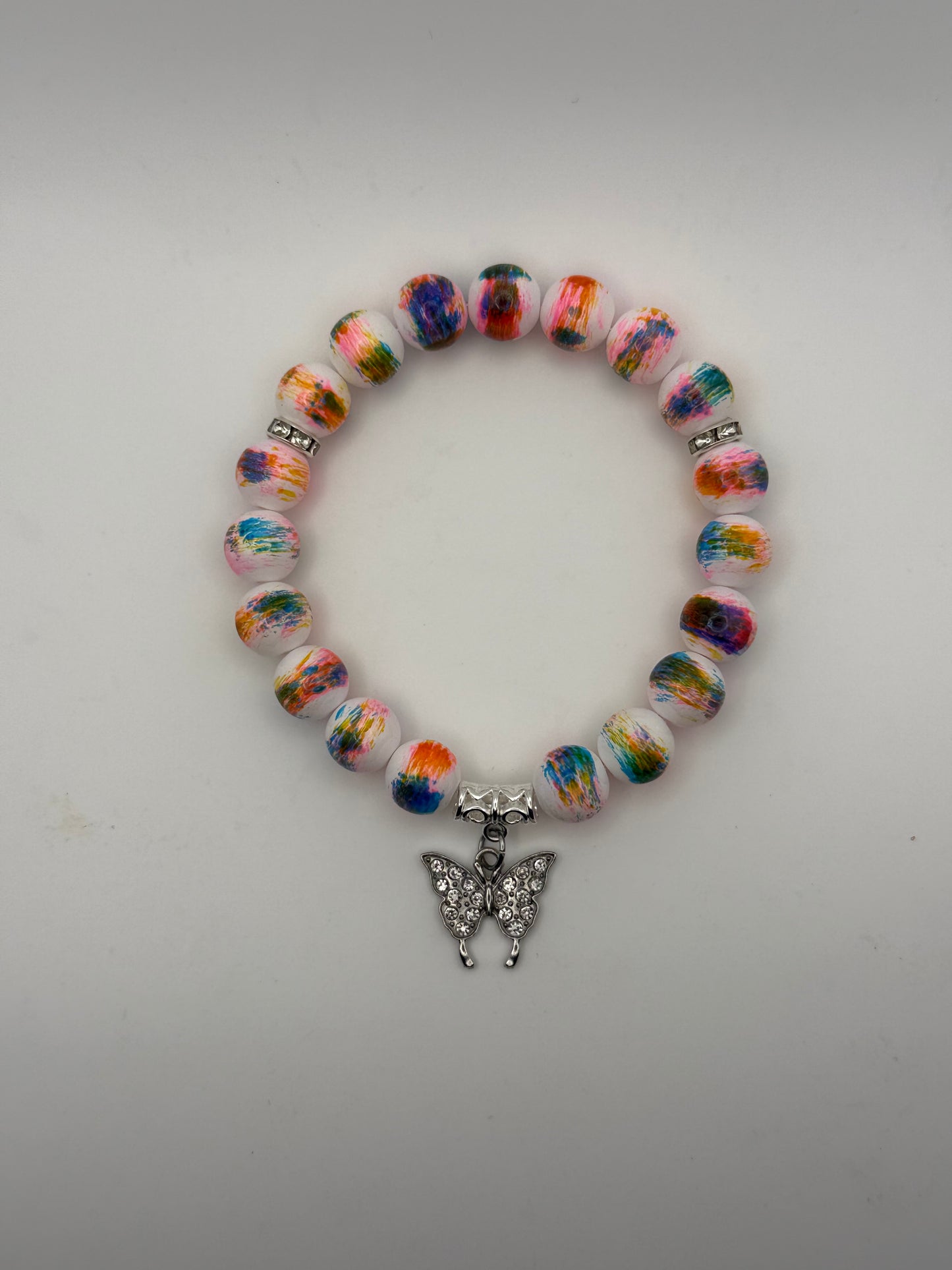 Colorful beaded bracelet with a silver charm on a light gray background
