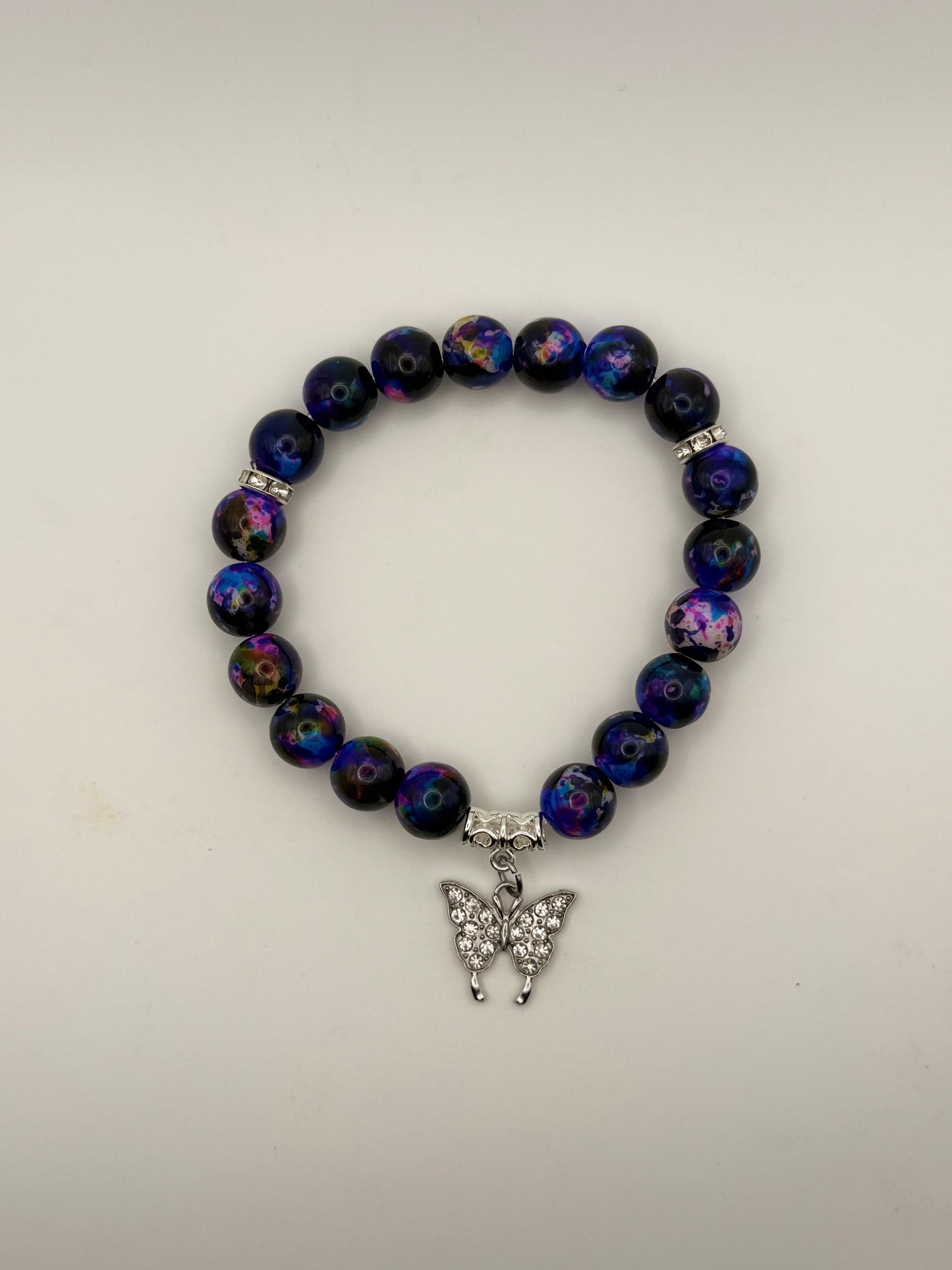 Beaded bracelet with a butterfly charm on a light gray background