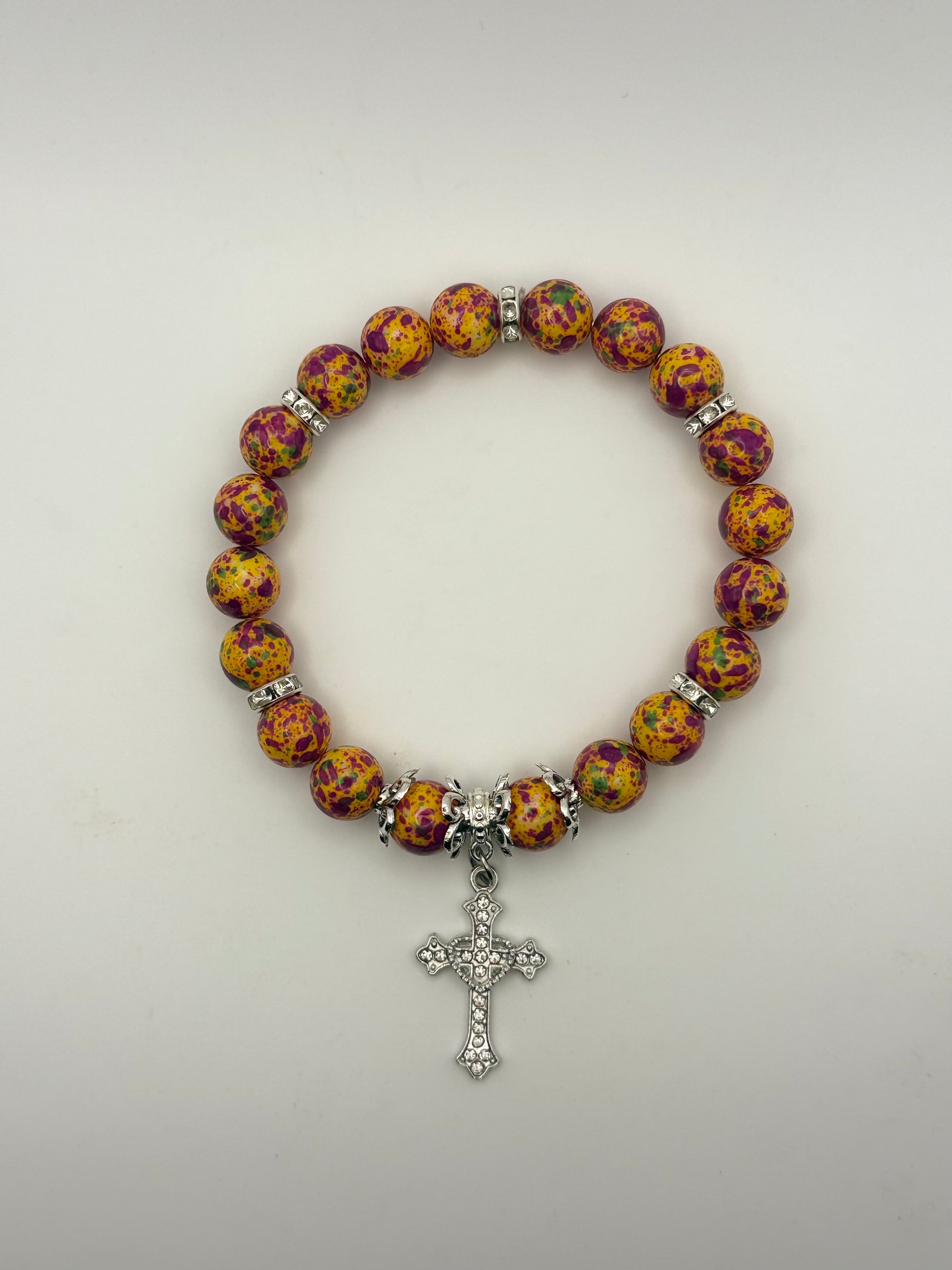 Bracelet with colorful beads and a silver cross charm on a light gray background