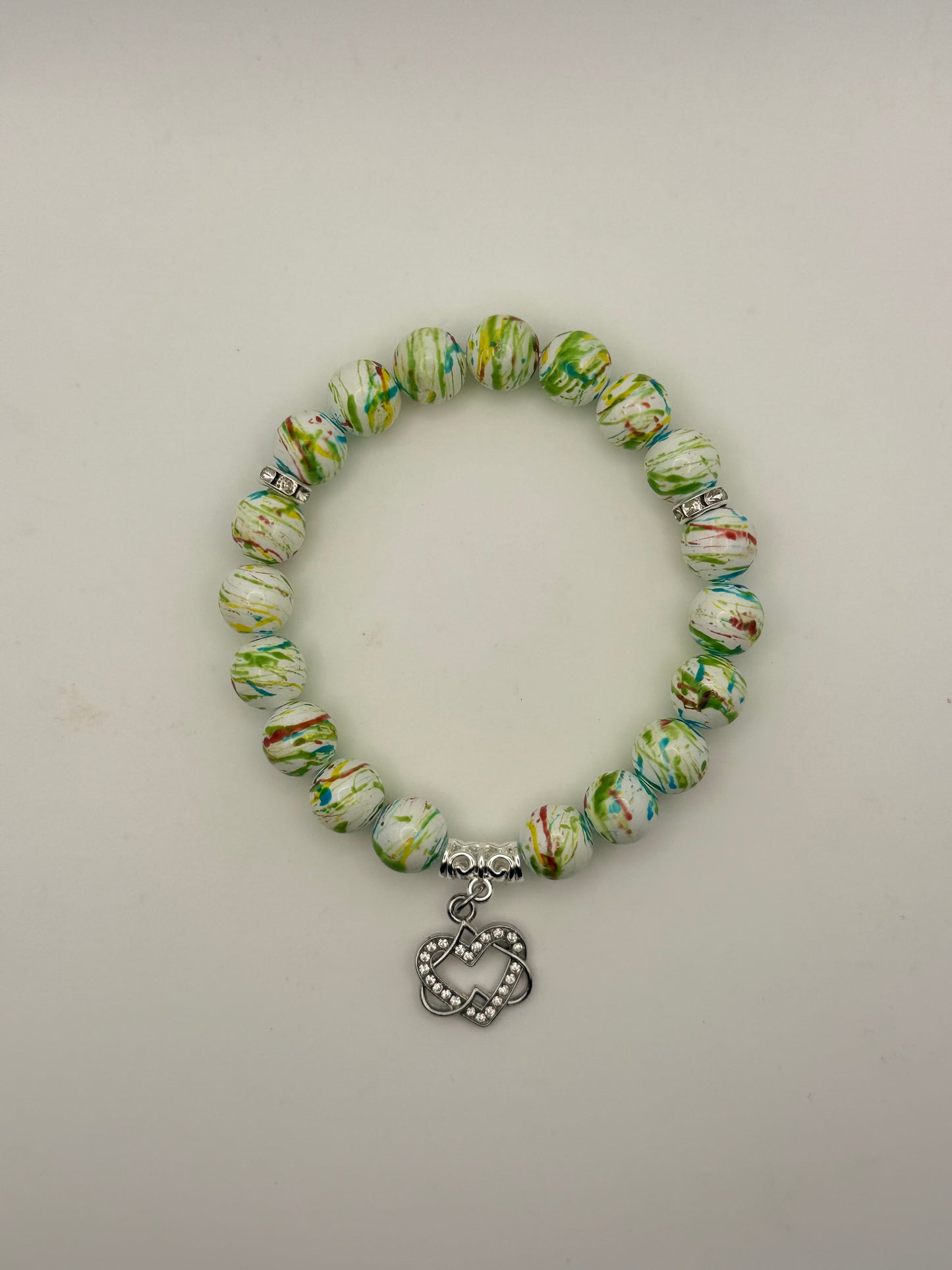 Beaded bracelet with a heart charm on a light gray background