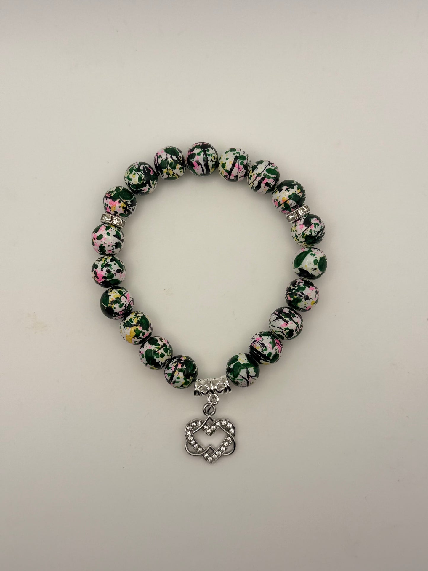 Beaded bracelet with floral pattern and heart charm on a light gray background