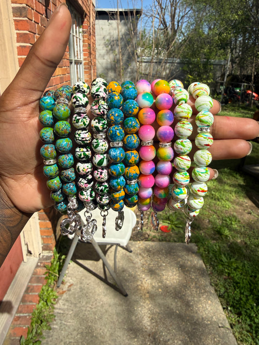 Stack of colorful beaded bracelets held in a hand with a blurred outdoor background