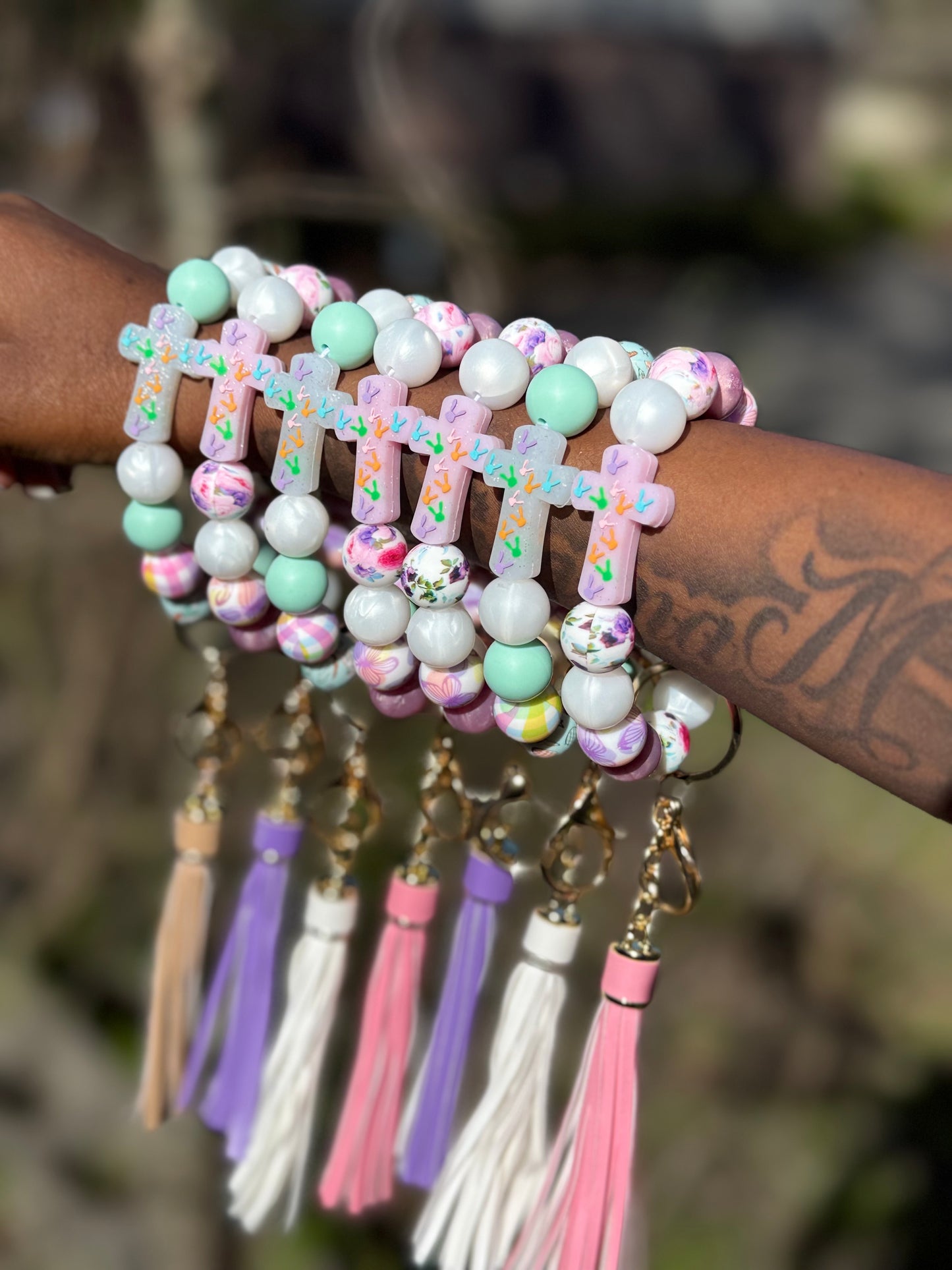Colorful beaded bracelets with tassels on a wrist against a blurred natural background
