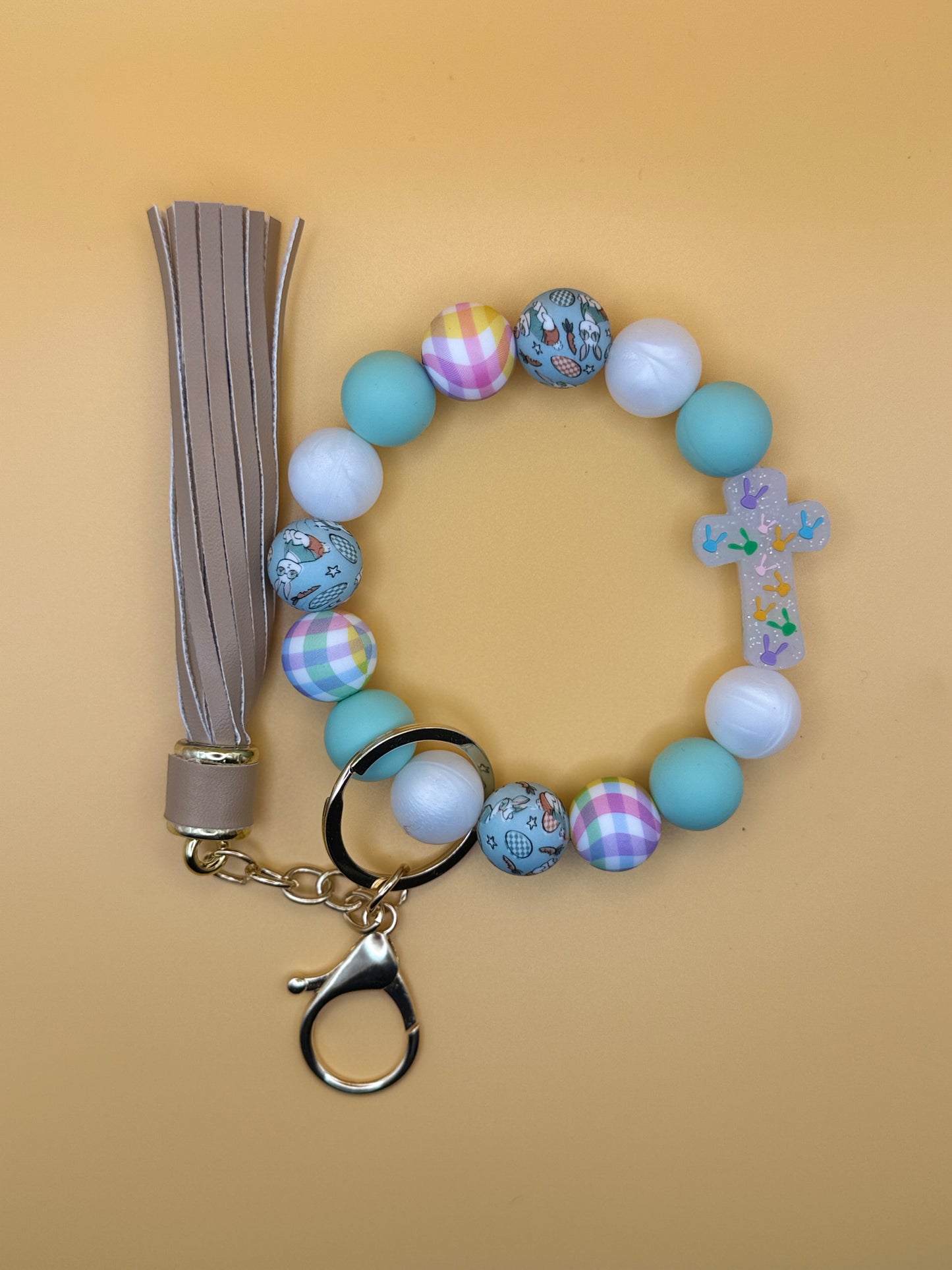 Beaded keychain with colorful beads and a tassel on a beige background