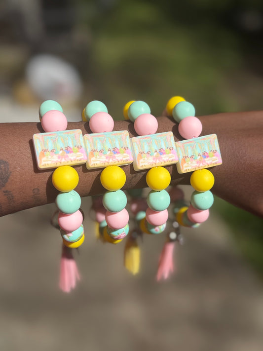 Colorful beaded bracelet with square charms on a wrist against a blurred natural background