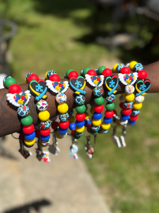 Colorful beaded bracelets with heart and flower designs on a wrist against a blurred natural background.